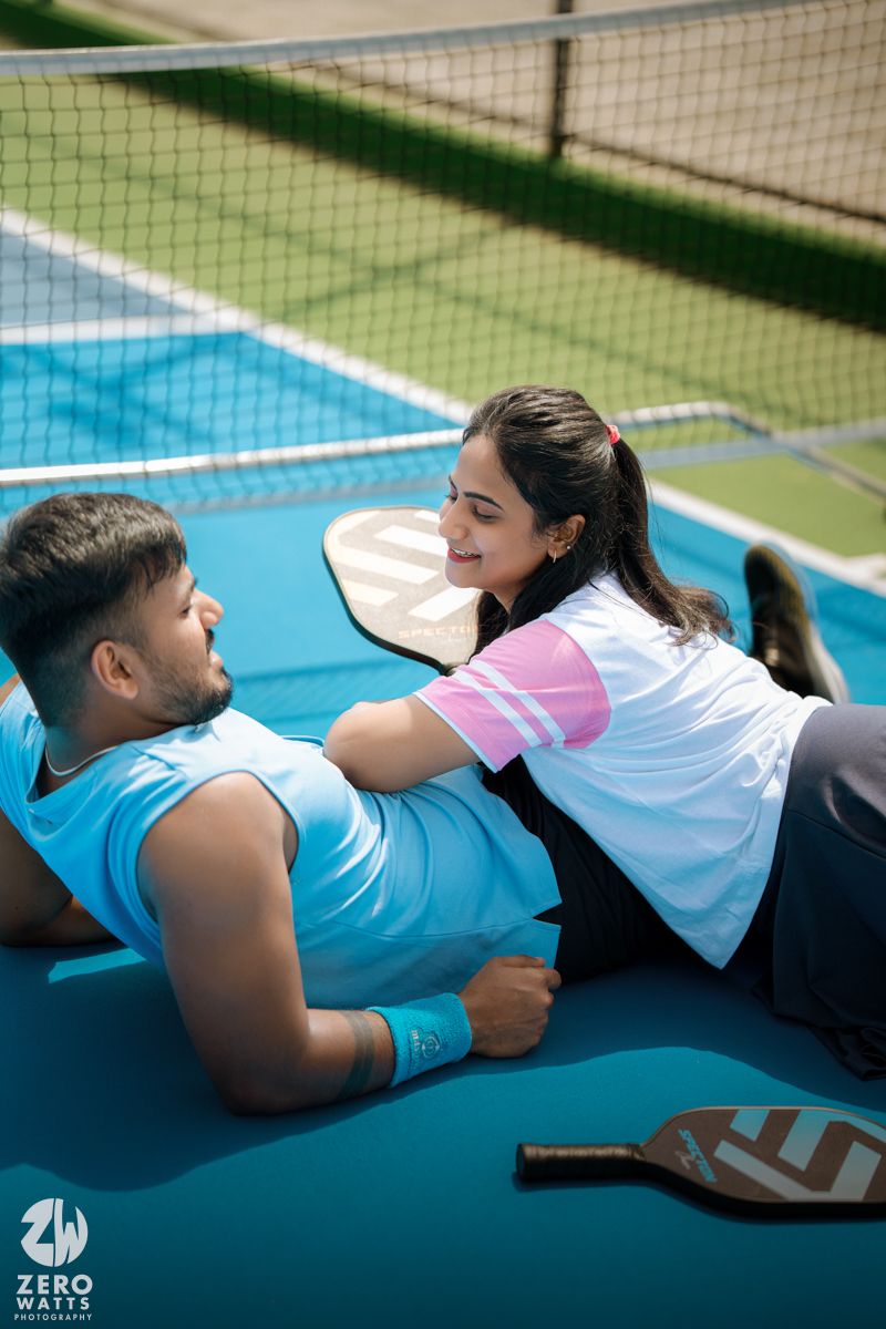 Couple relaxing on blue pickleball court after their game.