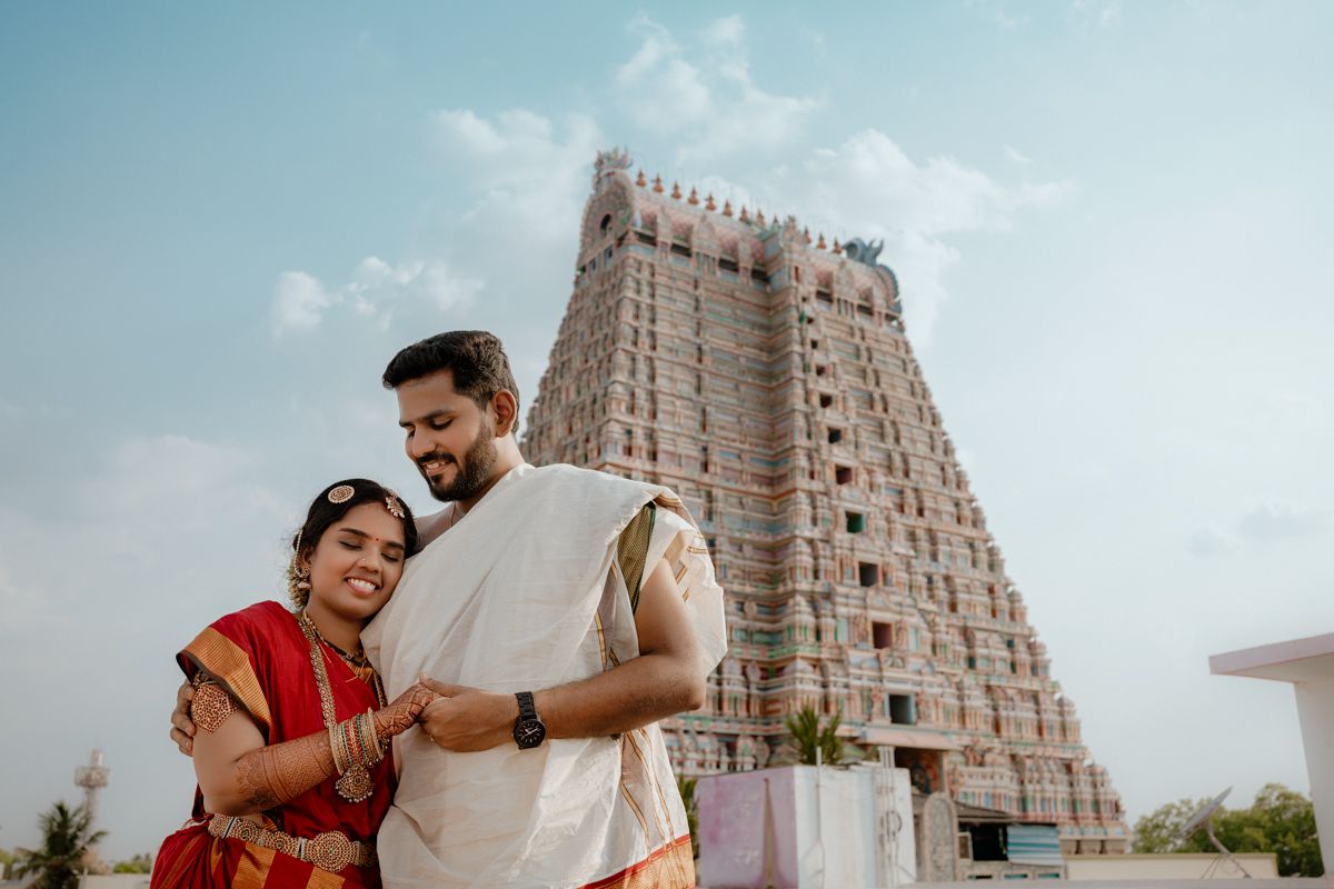 Traditional couple in Indian attire smiling while standing in front of the Ranganathaswamy Temple in Tamil Nadu.