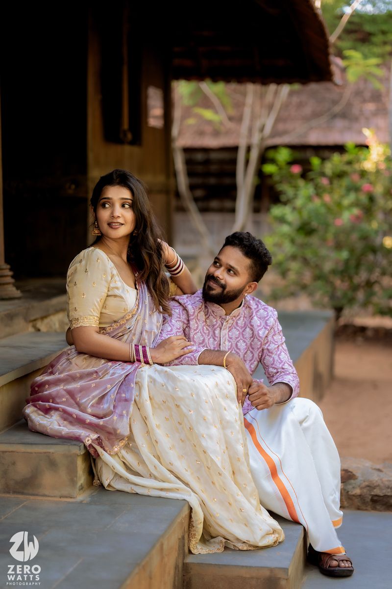Couple in traditional Indian attire sitting on rustic stone steps during outdoor photoshoot.
