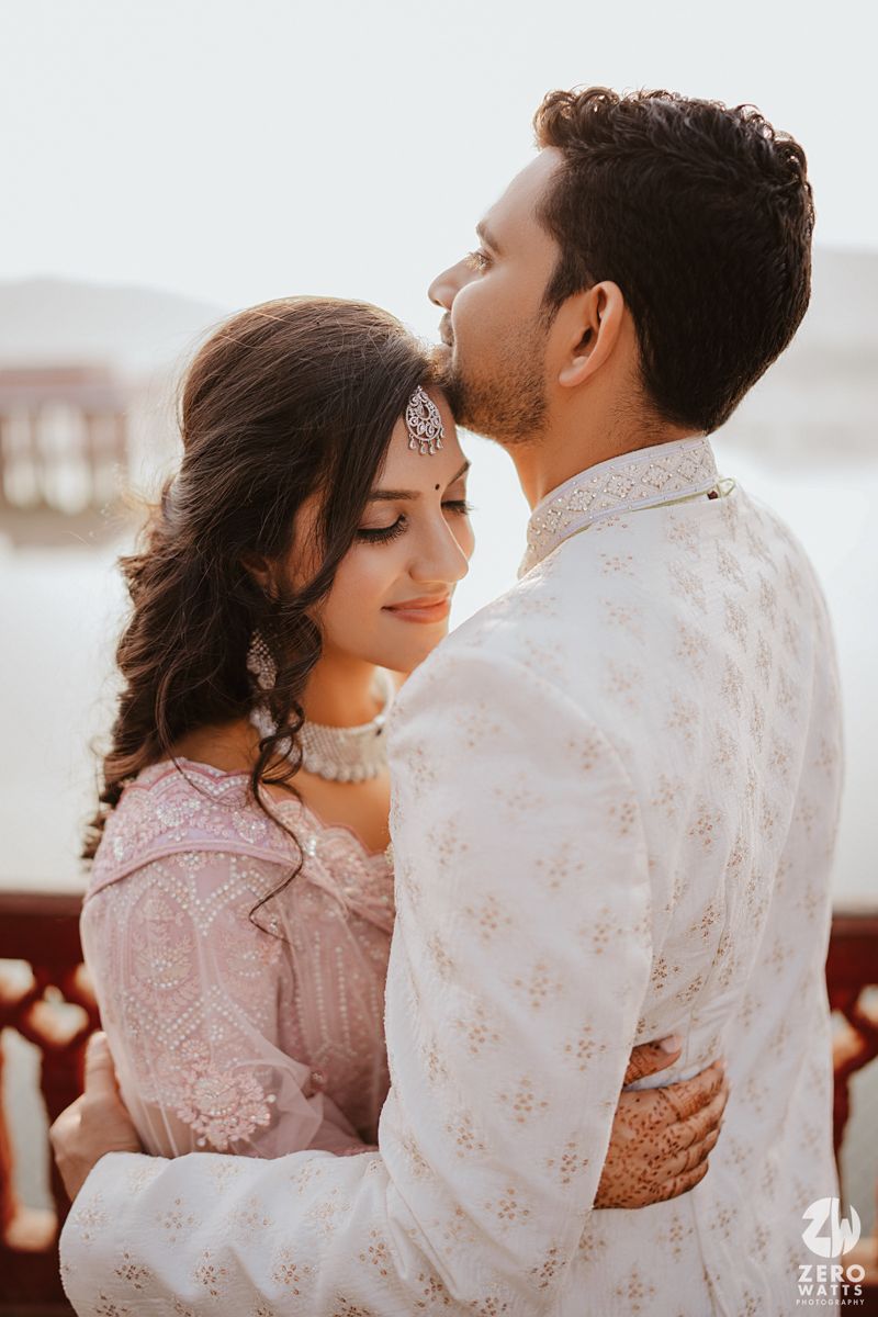 A romantic couple in traditional Indian attire embrace during a sunset photo session.