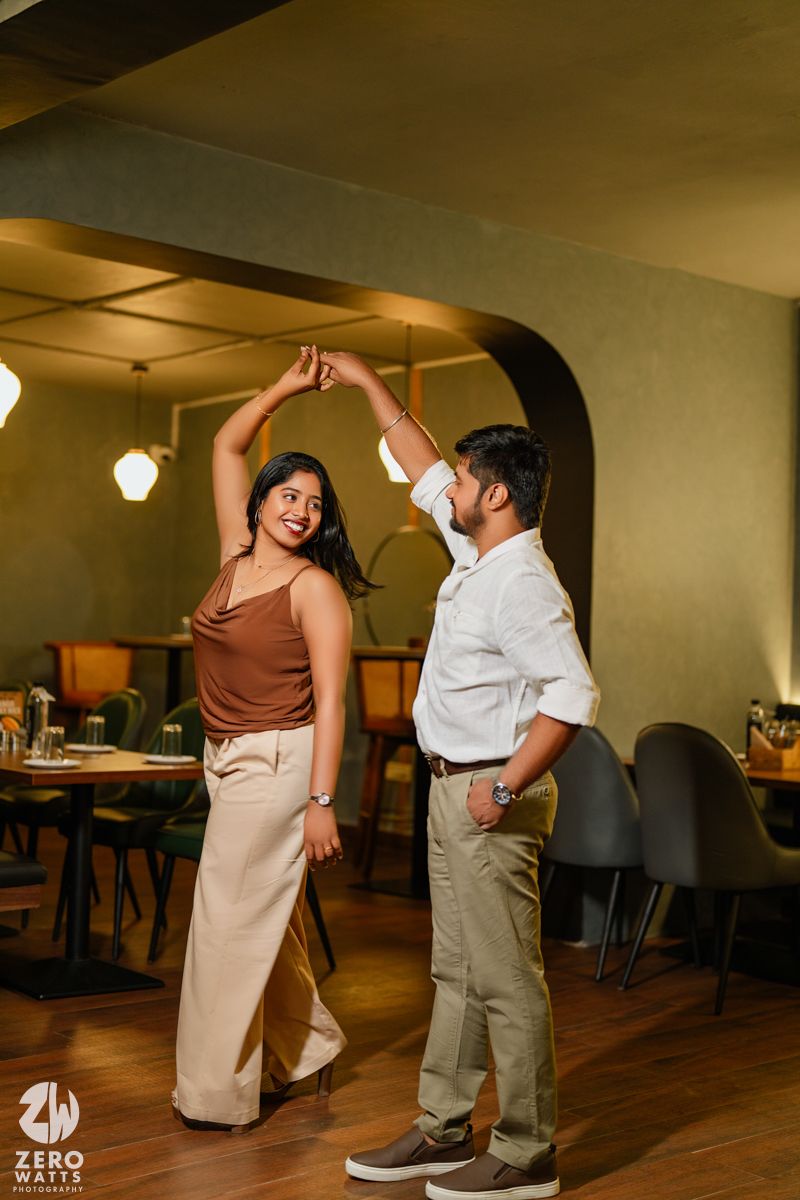A couple dancing together in a warmly lit restaurant interior with wooden floors.