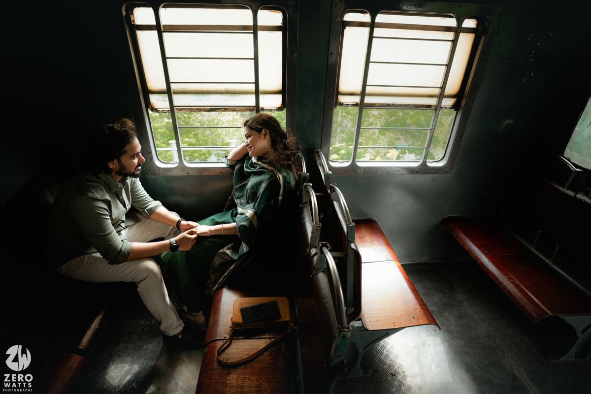 A romantic couple shares an intimate moment while sitting in a train compartment near the window.