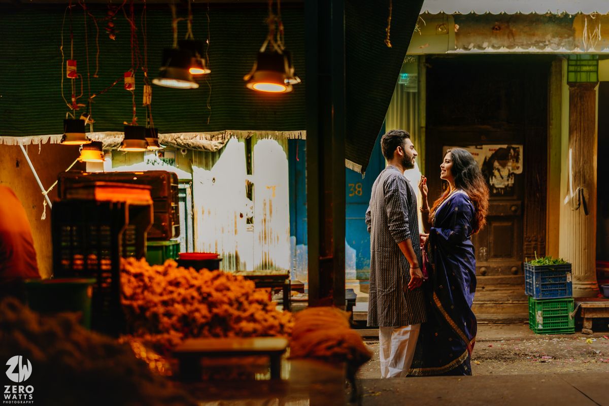 A moody street scene in India with glowing orange food displays and traditional clothing in soft evening light.