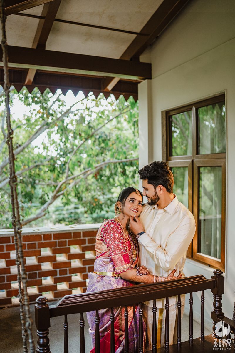 Romantic couple sharing a tender moment on a rustic wooden porch with green foliage in the background.