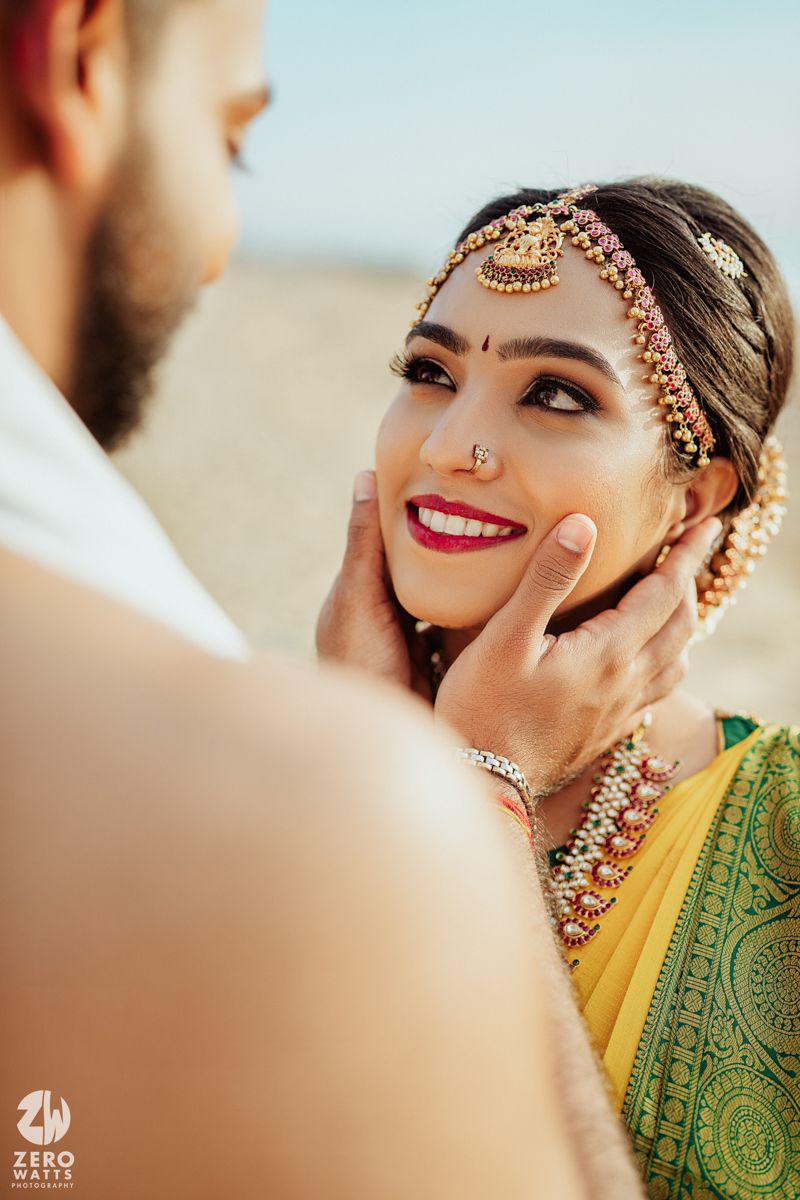 Beautiful traditional Indian bride in yellow and green saree with ornate jewelry and makeup in romantic moment.