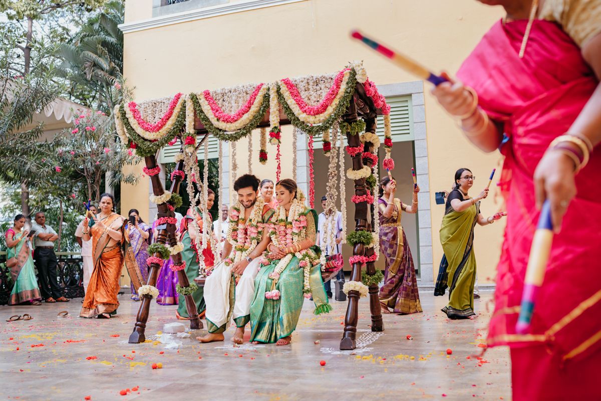 Festive Indian wedding ceremony with guests dancing and celebrating under a decorated mandap outdoor.