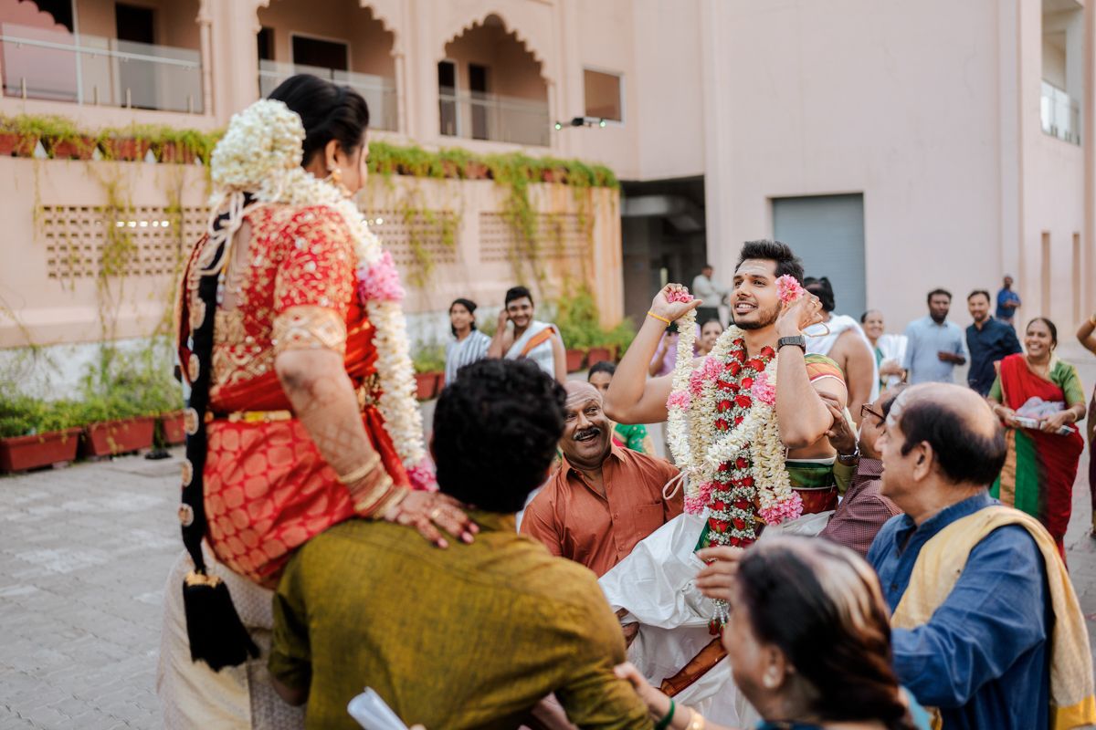 Wedding celebration scene with guests seated on the ground during a traditional Indian ceremony.