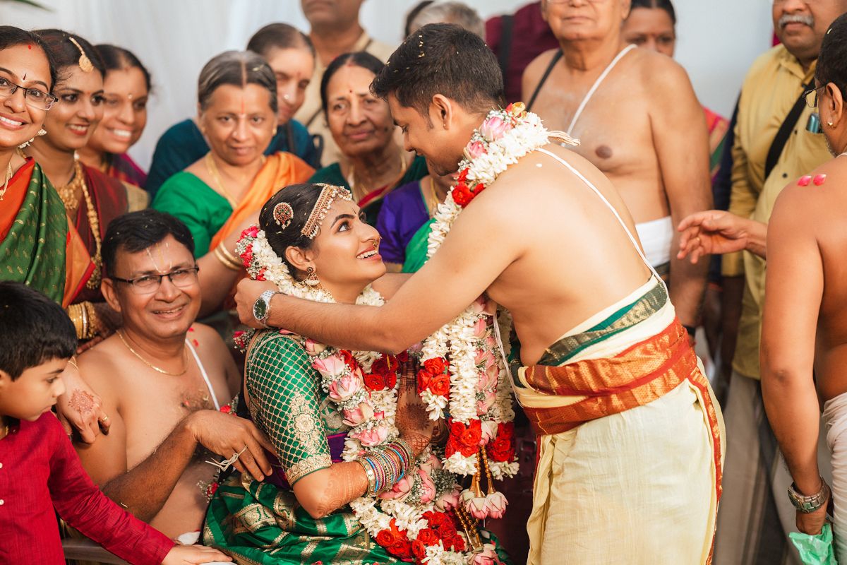 Traditional South Indian wedding ceremony with colorful attire and garlands during an emotional ritual moment.