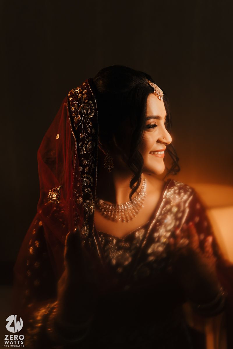 A glowing candlelit portrait captures an elegantly dressed person in traditional South Asian bridal attire with jewelry.
