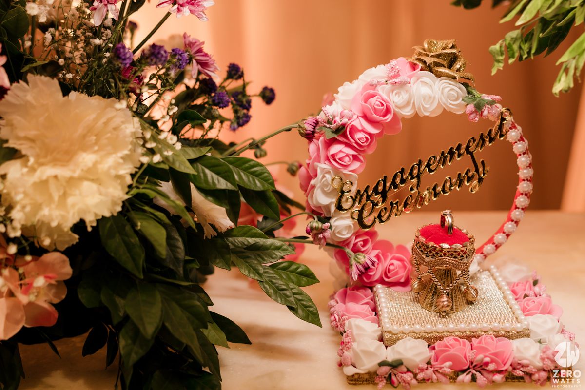 An elegant engagement decor setup with pink roses, ornamental ring holder and decorative elements.