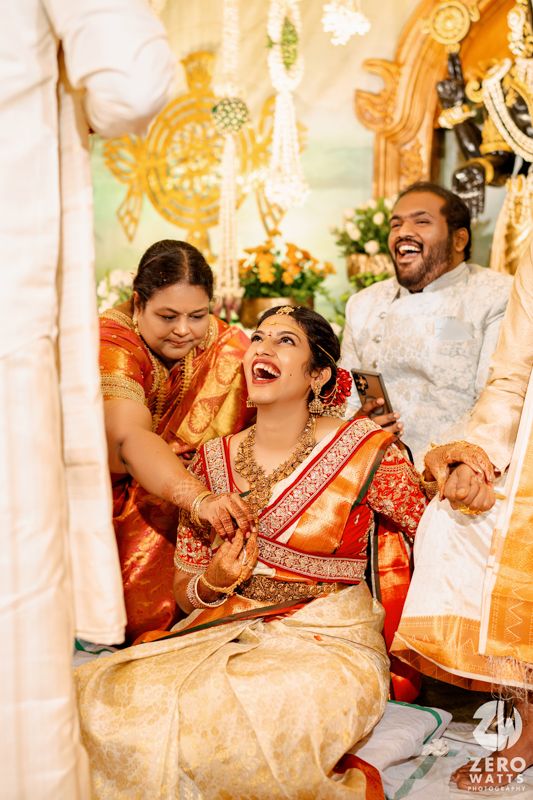 Close-up of bride wearing traditional gold jewelry and red silk saree during South Indian wedding.