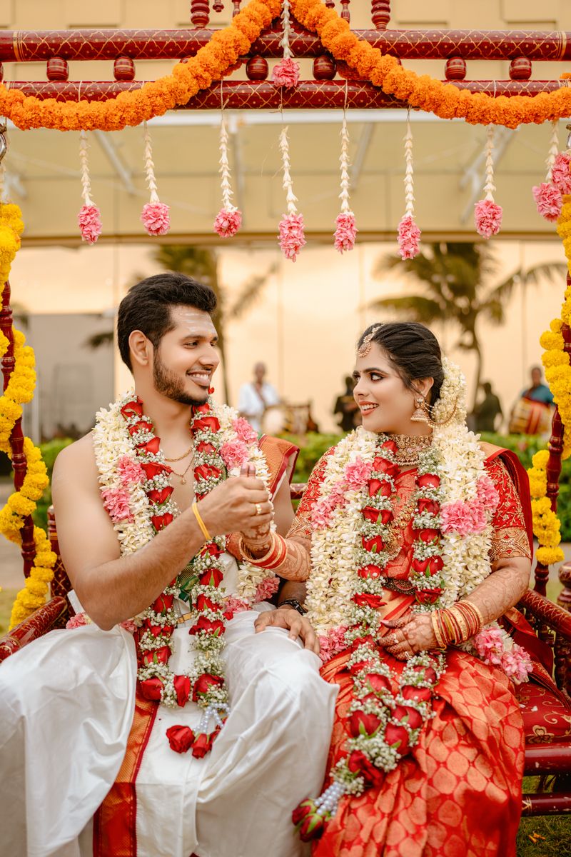 Traditional South Indian wedding ceremony with colorful floral decorations and marigold garlands under an ornate mandap.