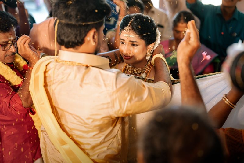 Person performing a traditional Indian wedding ritual with a crowd of onlookers during a vibrant ceremony.