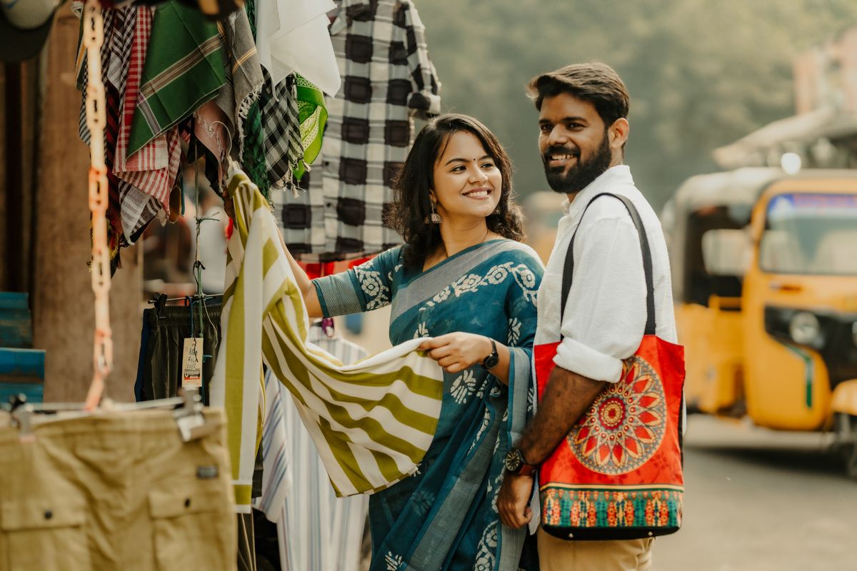 A couple shops together at a colorful Indian street market with rickshaw in the background.