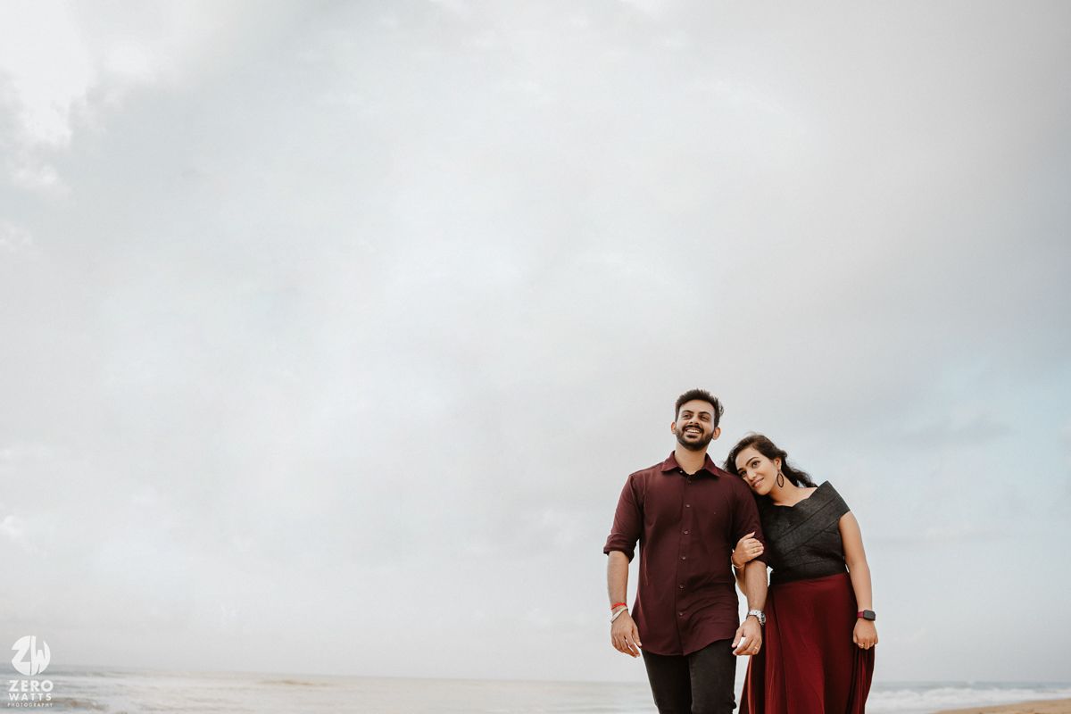 Casual couple portrait against cloudy sky backdrop in minimalist composition.