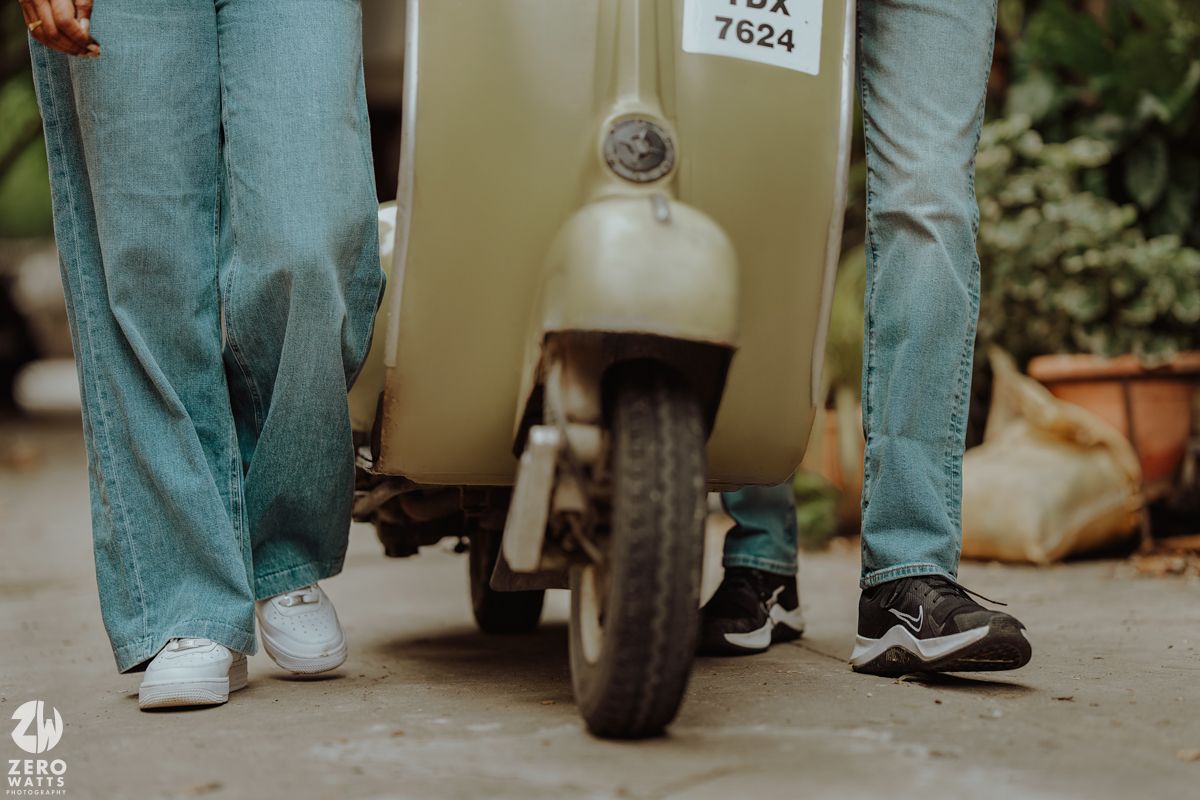 Close-up shot of feet and scooter wheel on pavement showing casual shoes and denim jeans.