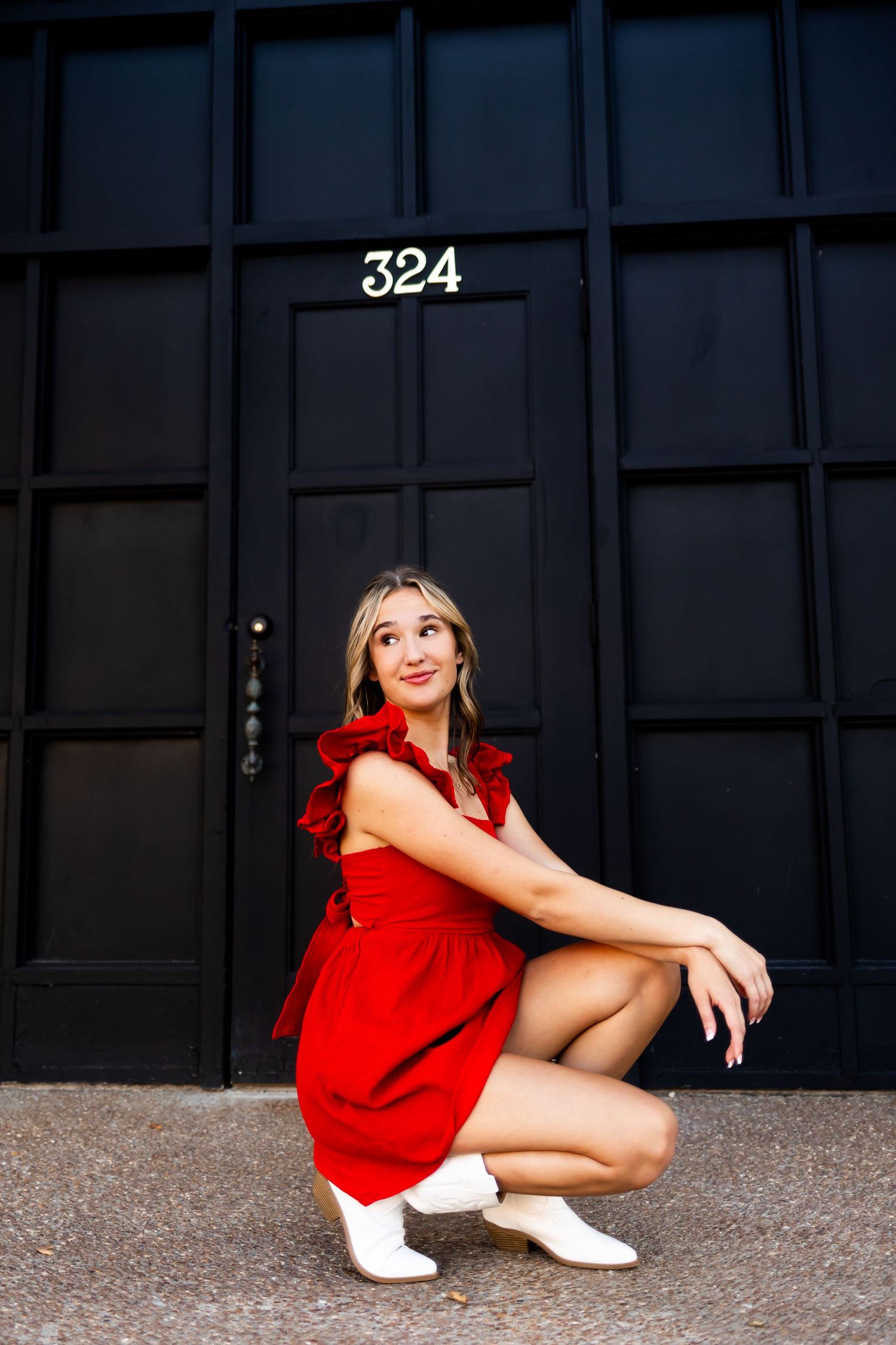 A stylish red dress portrait in front of a black door numbered 324.