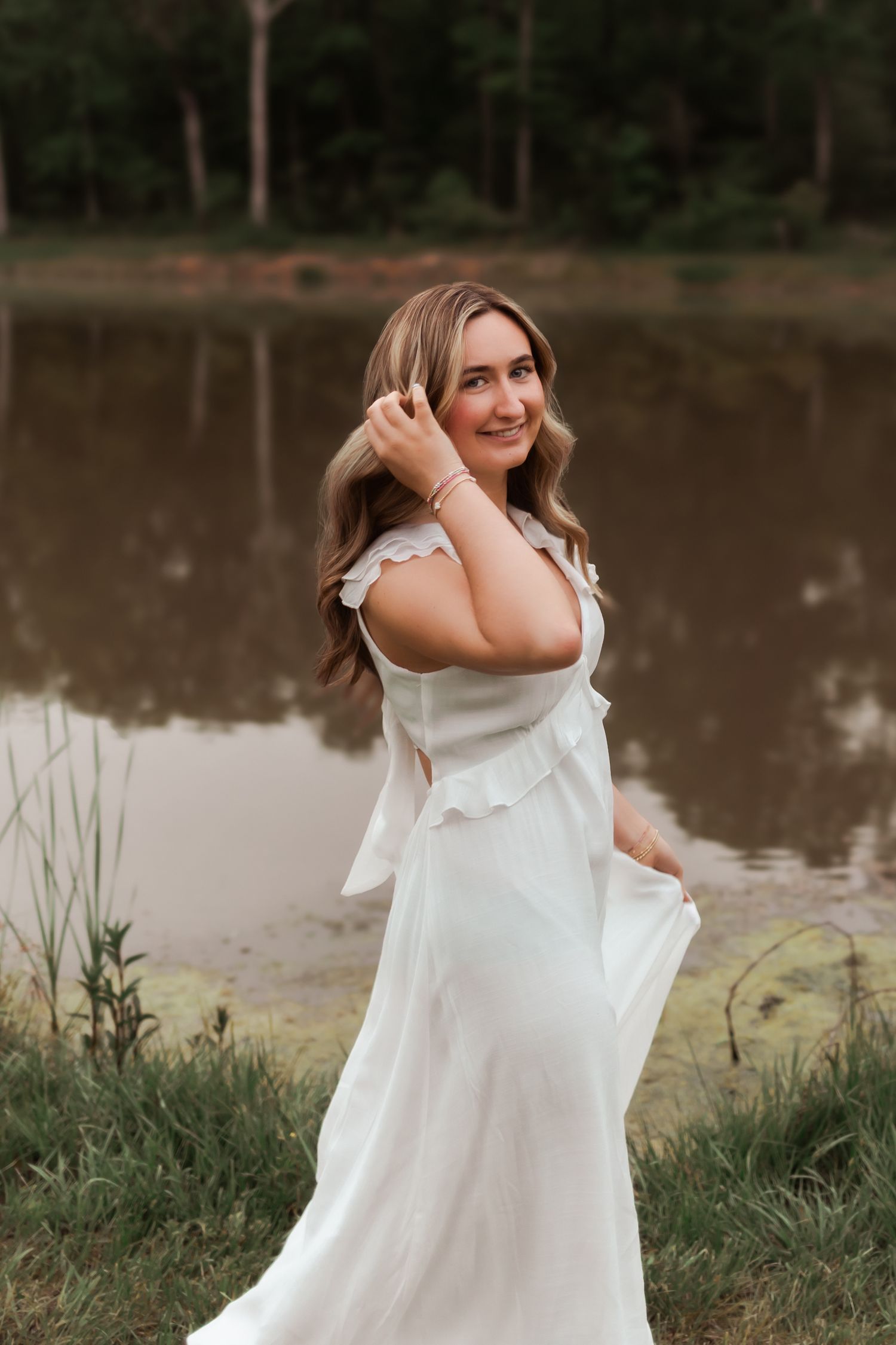 Candid moment by lakeside in flowing white dress during golden hour.