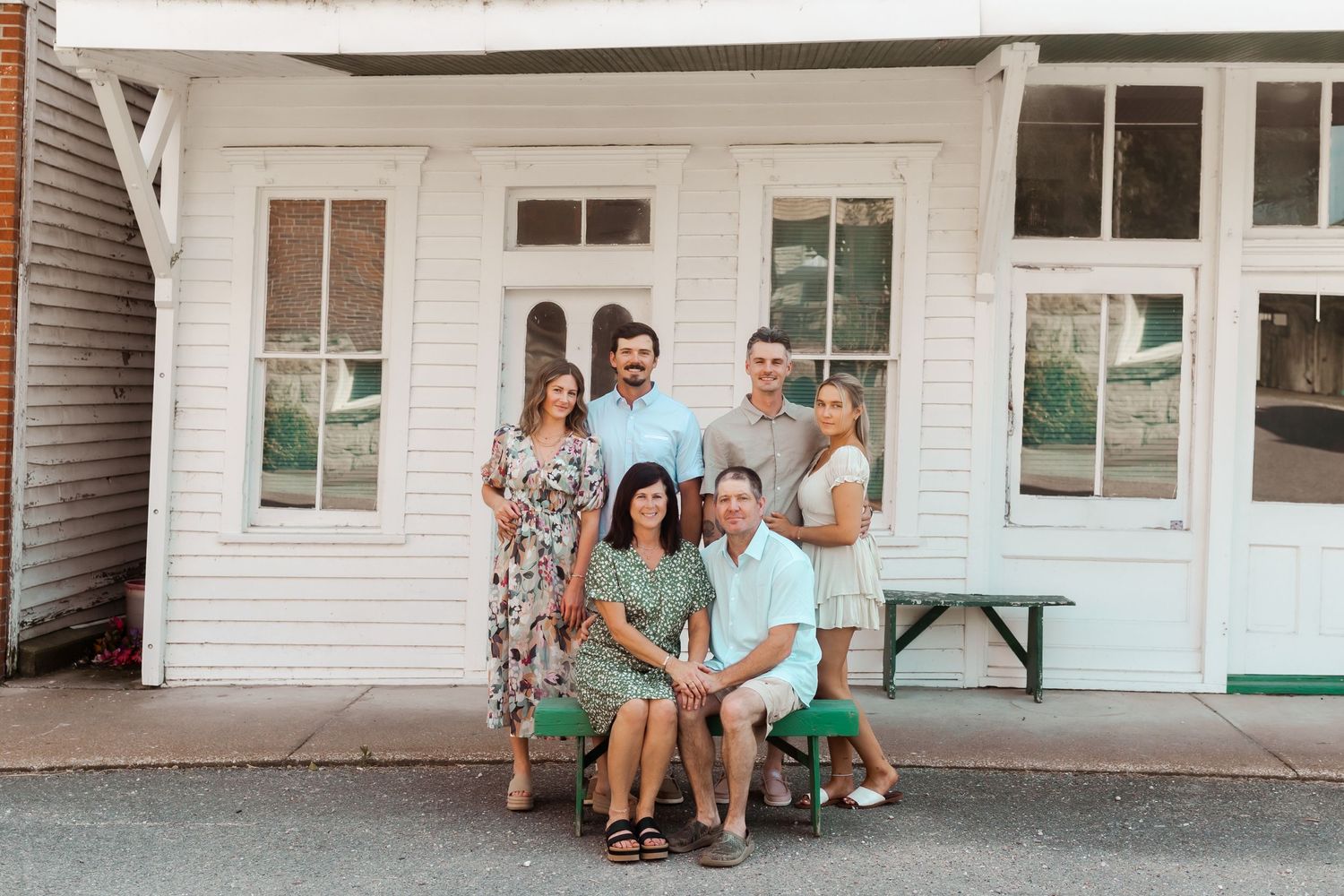 Family group portrait on white porch of vintage building with classic architectural details.