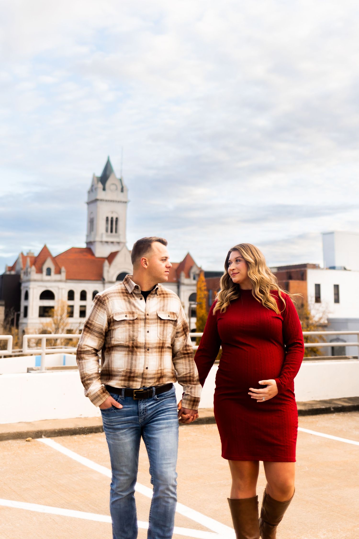 Stylish couple walking together in front of historic building with church tower during autumn season.