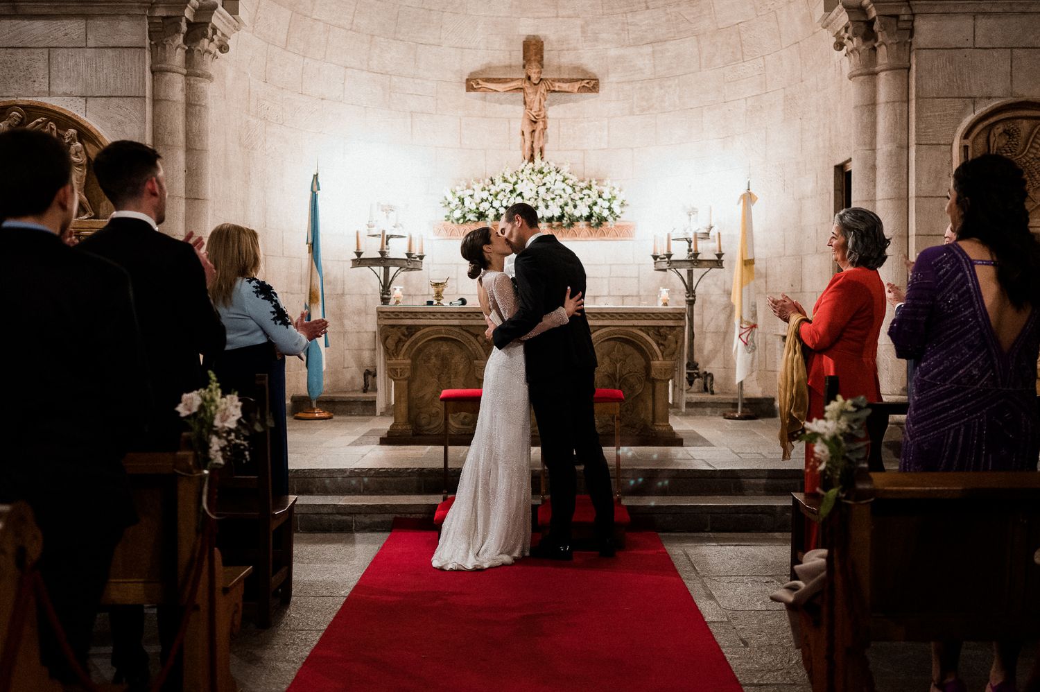 Wedding ceremony in traditional church with stone columns and crucifix at altar.
