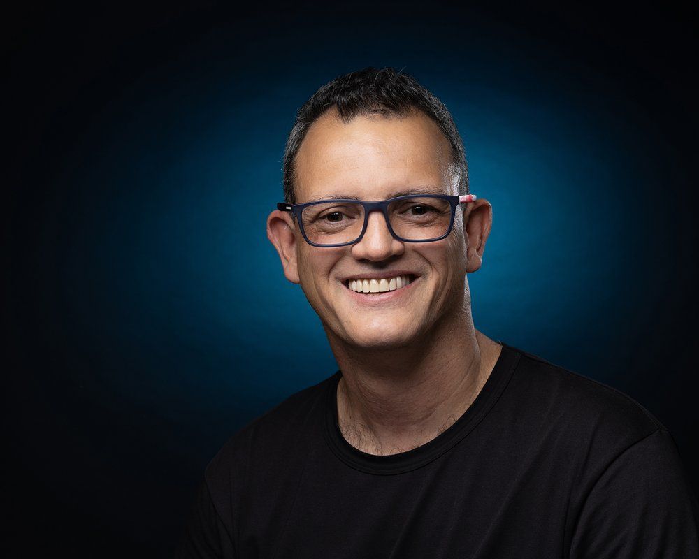 Portrait of photographer wearing glasses against blue background gradient.