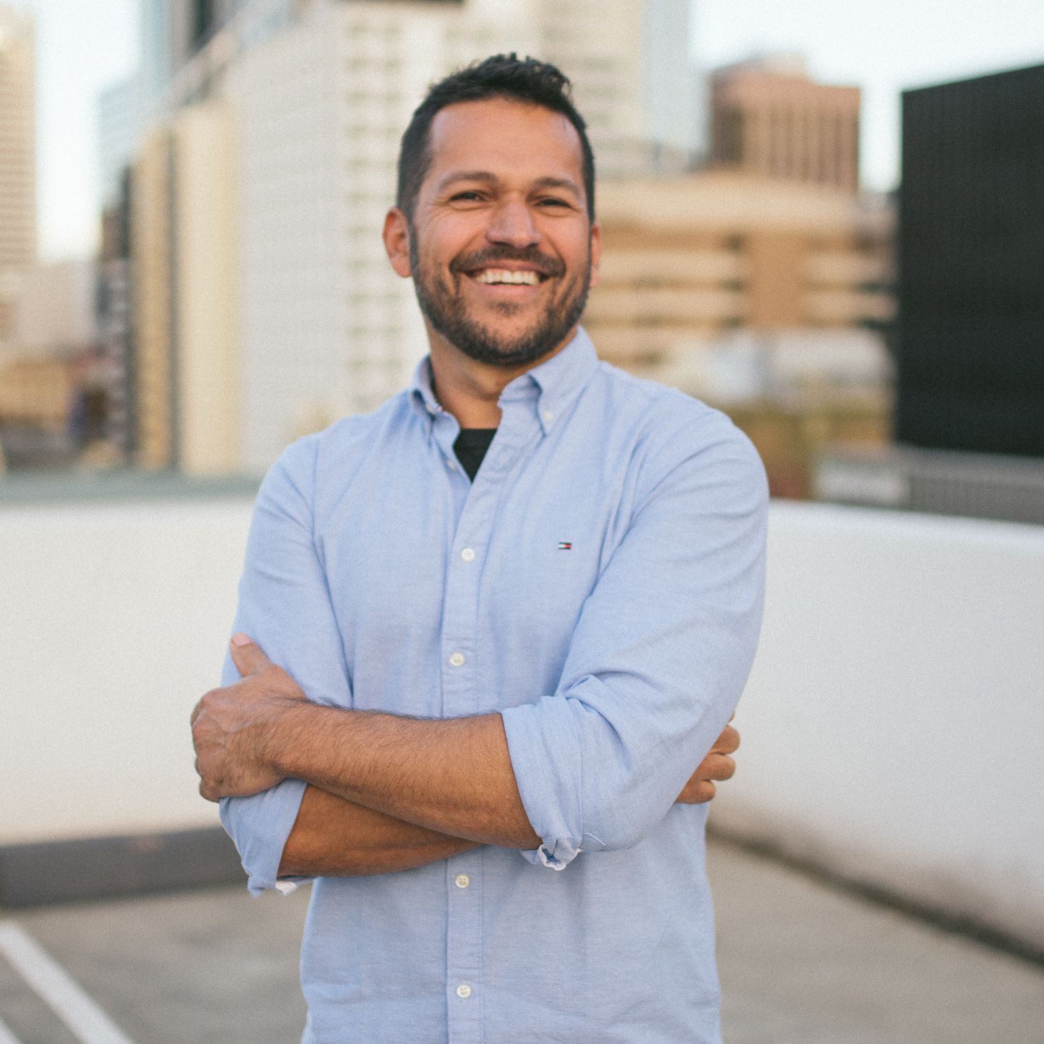 Professional photographer wearing light blue button-down shirt on urban rooftop.