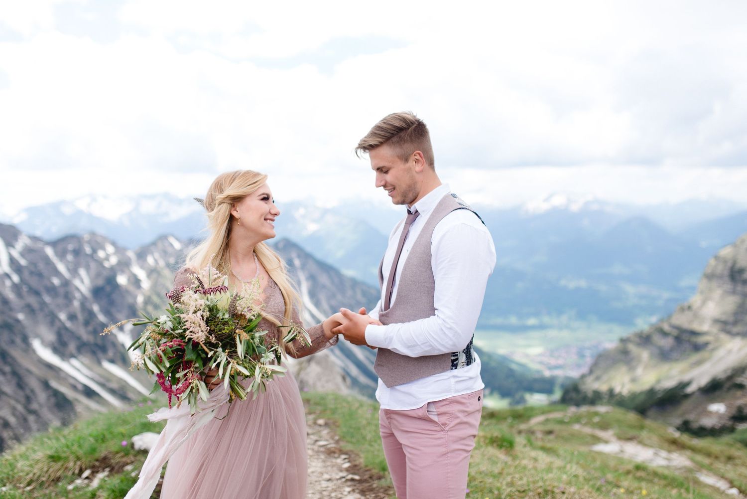 Junges paar am Nebelhorn halten sich an der Hand mit Brautstrauß