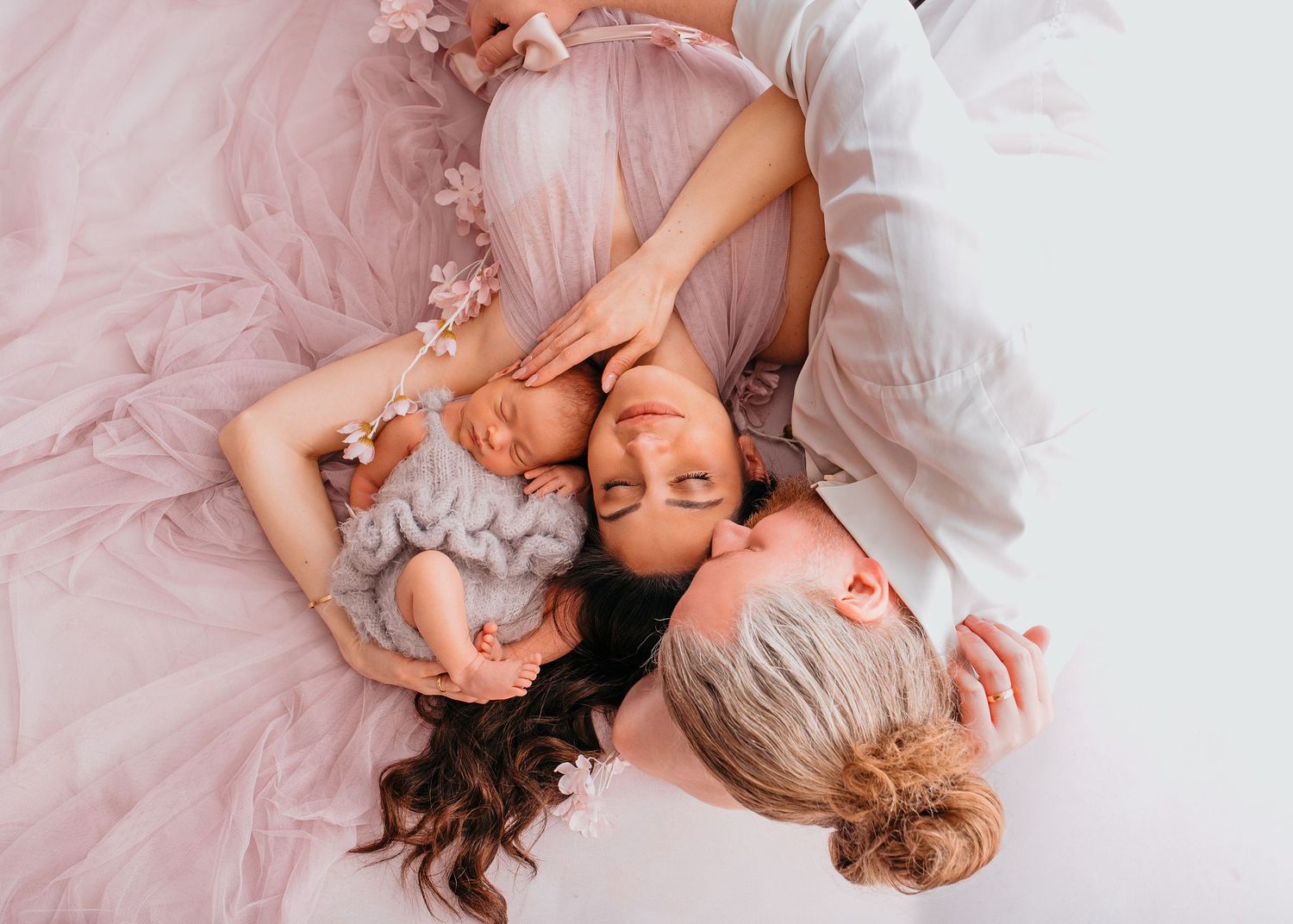 Mama und Papa liegend am Boden mit neugeborenem Mädchen