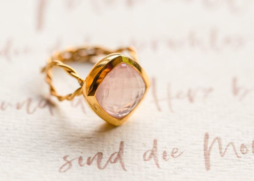 Ring in Gold mit Rosenquarz auf einem Schriftstück