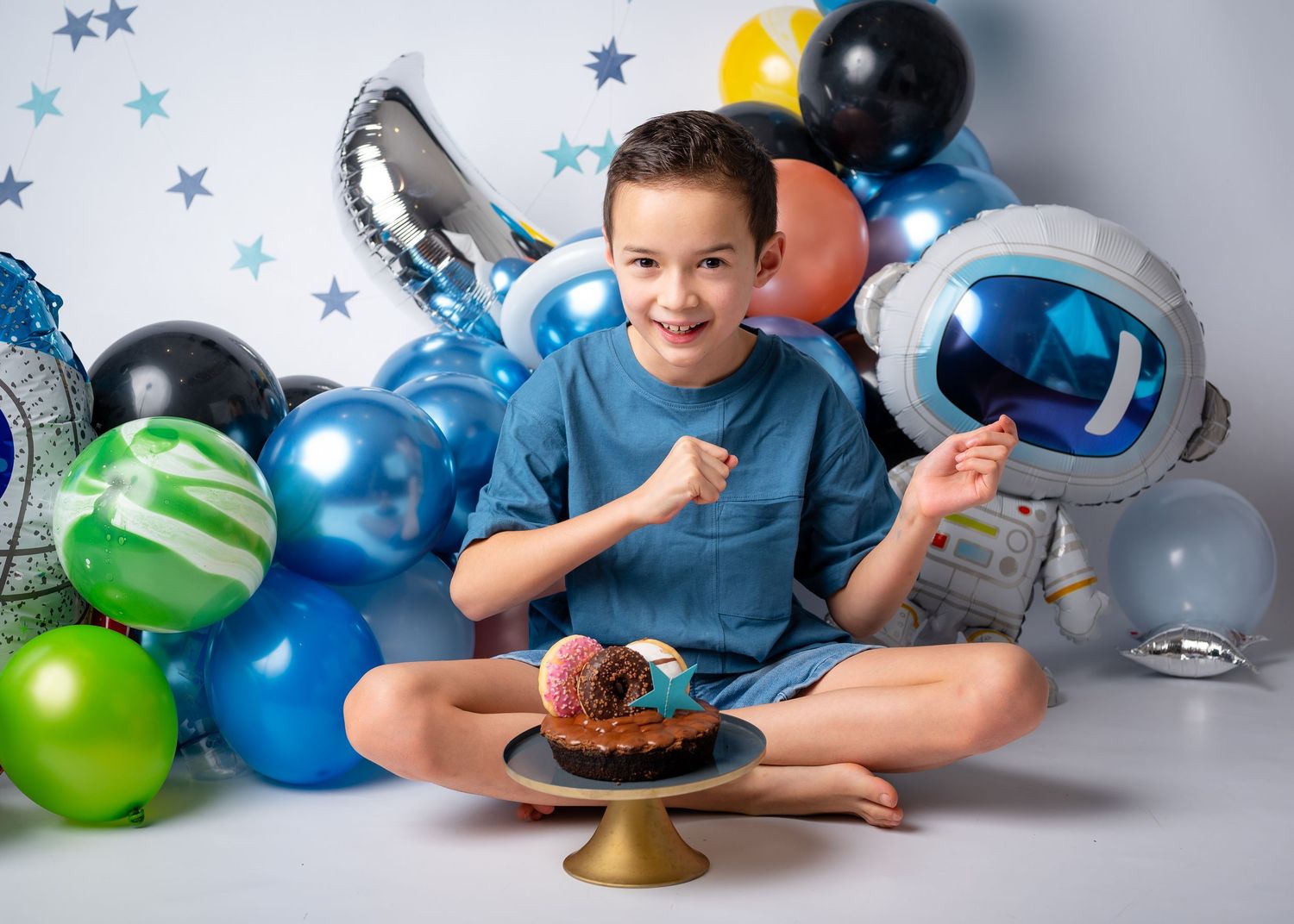 Luftballondekoration zum Thema Weltraum Junge der Tanzt vor einer mini Torte