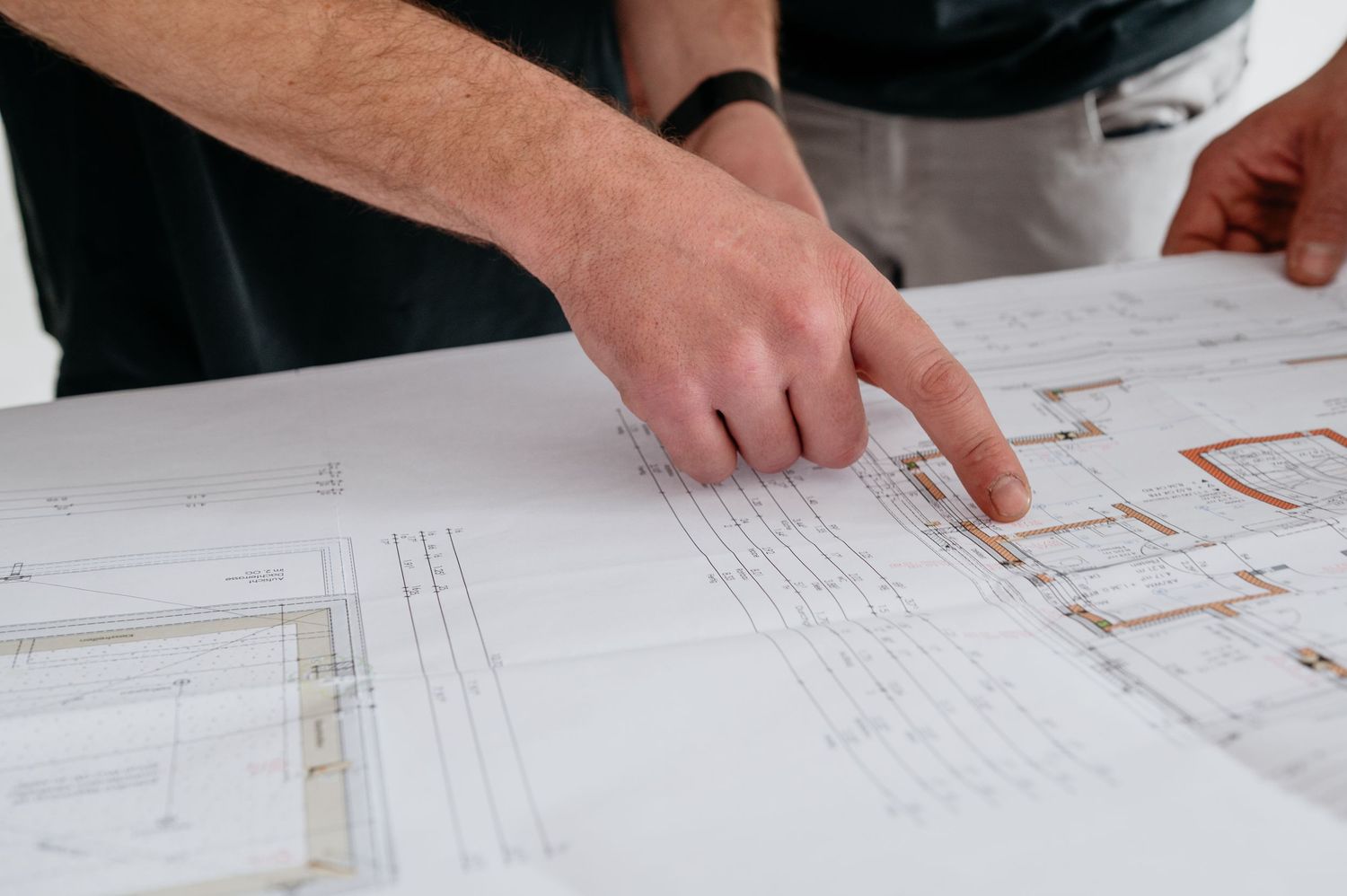 Mann zeigt auf Bauplan mit dem Finger