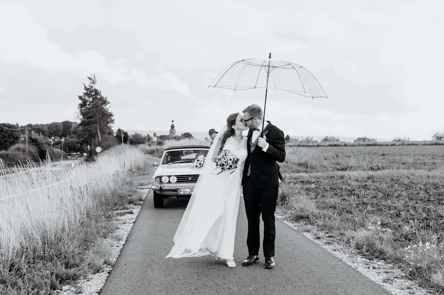 Authentische Hochzeitsreportage mit emotionalen Momenten. Brautpaar läuft vom Auto auf einem Feldweg