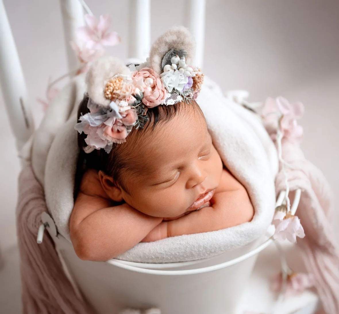 schlafendes Baby mit schwarzen haaren und Blütenkranz mit Ohren in einem Topf