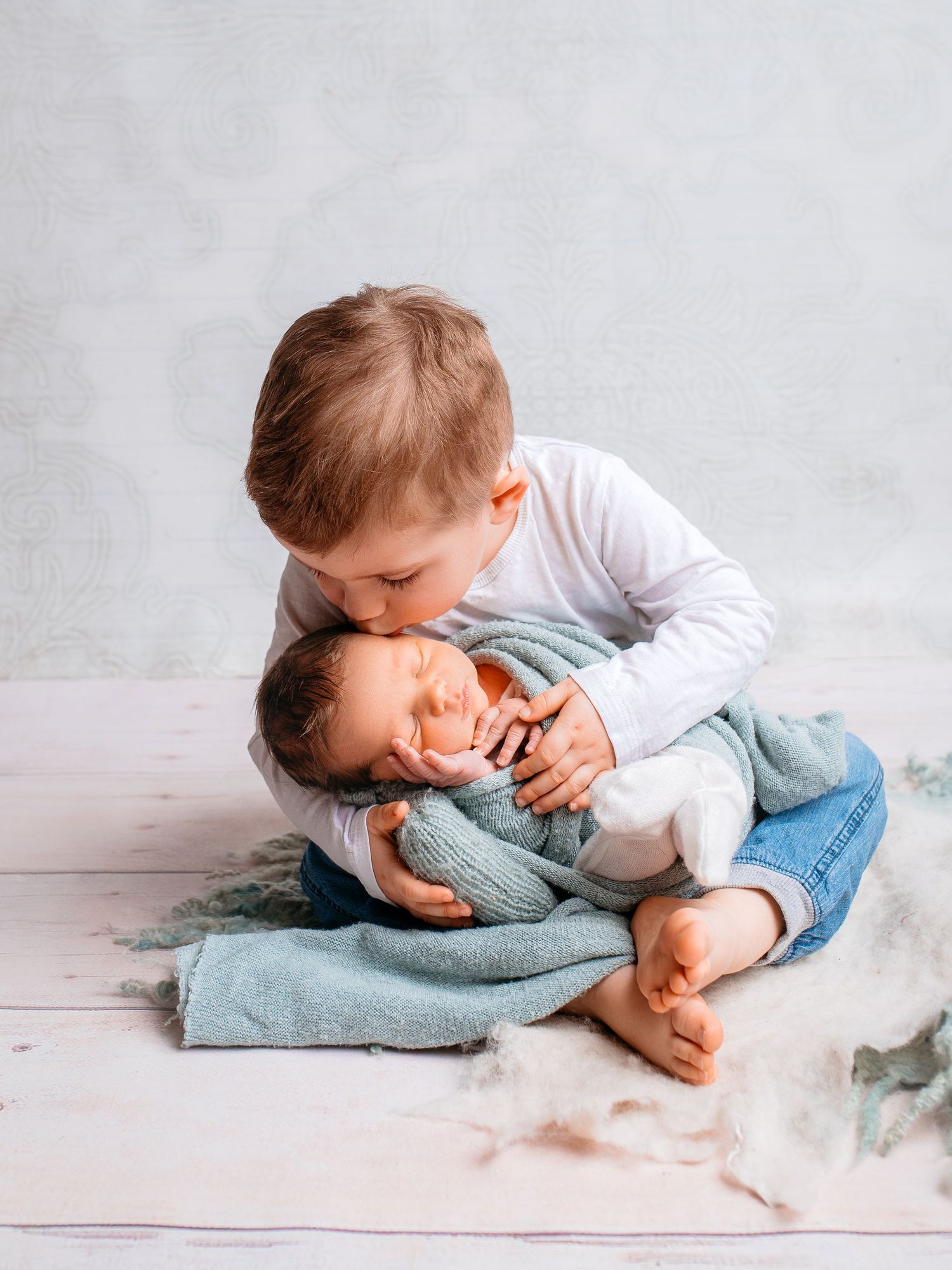 Fröhliches Kindershooting mit liebevollen Details. Newborn wird von Bruder geküsst