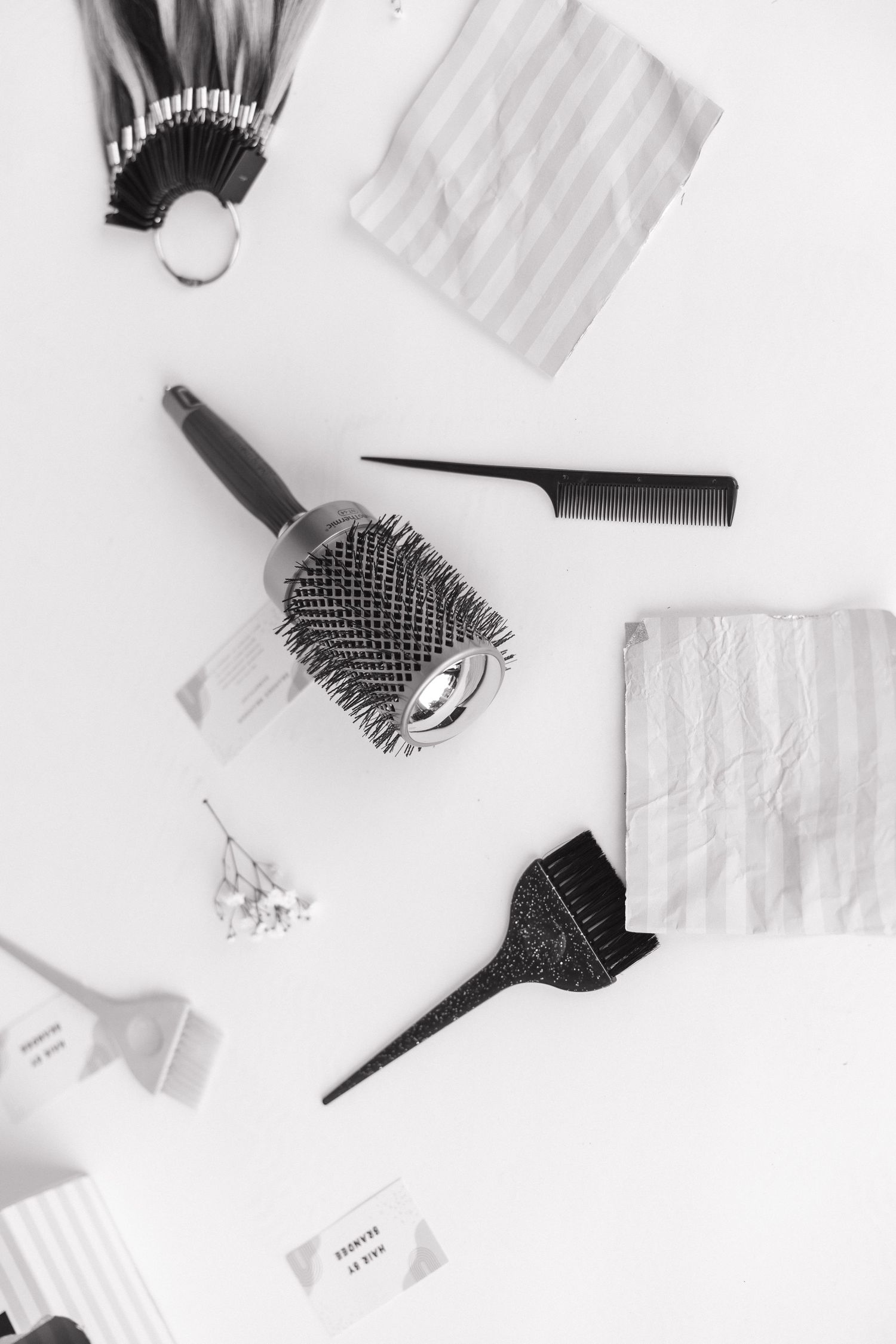 Flat lay of beauty and styling tools including combs and brushes on white background.
