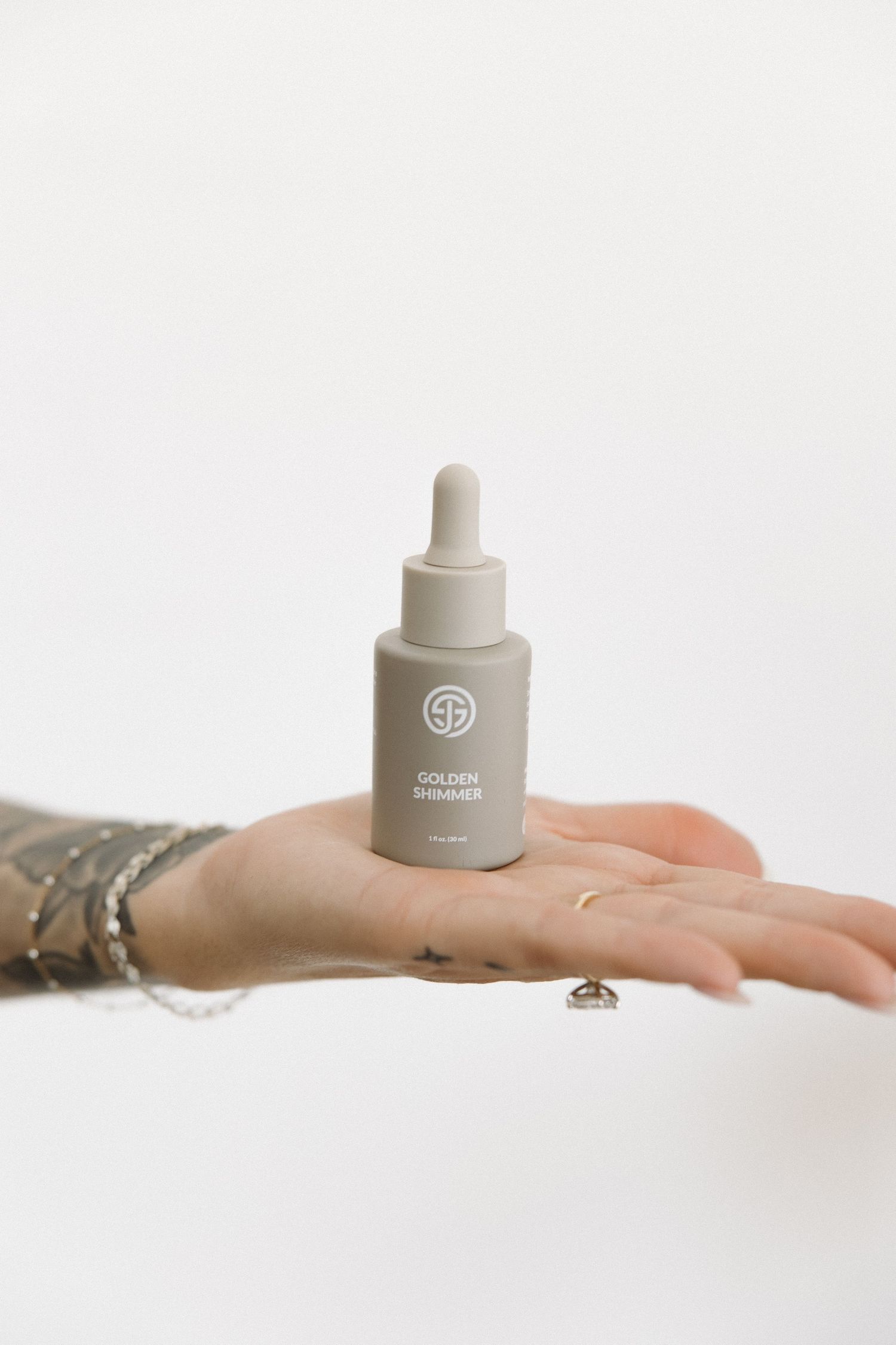 Minimal product photography showing a cosmetic dropper bottle balanced on hand.