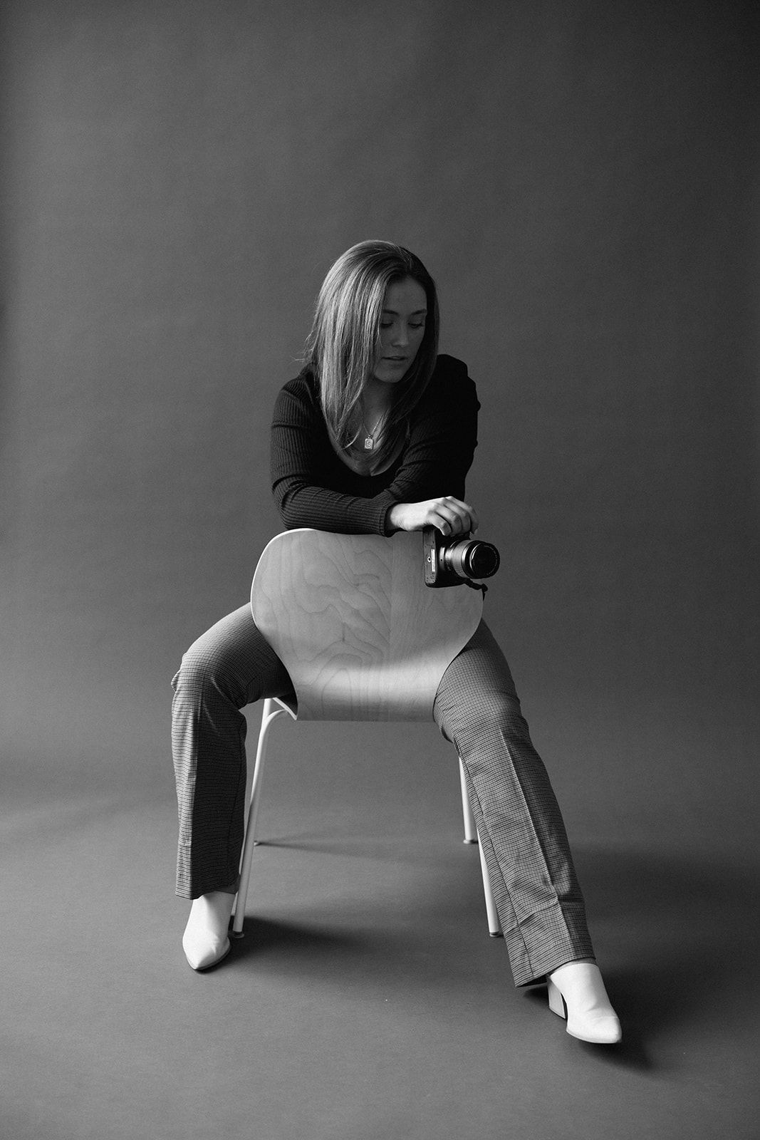 Dramatic black and white portraits showing artistic poses for photographer on a chair against dark background.