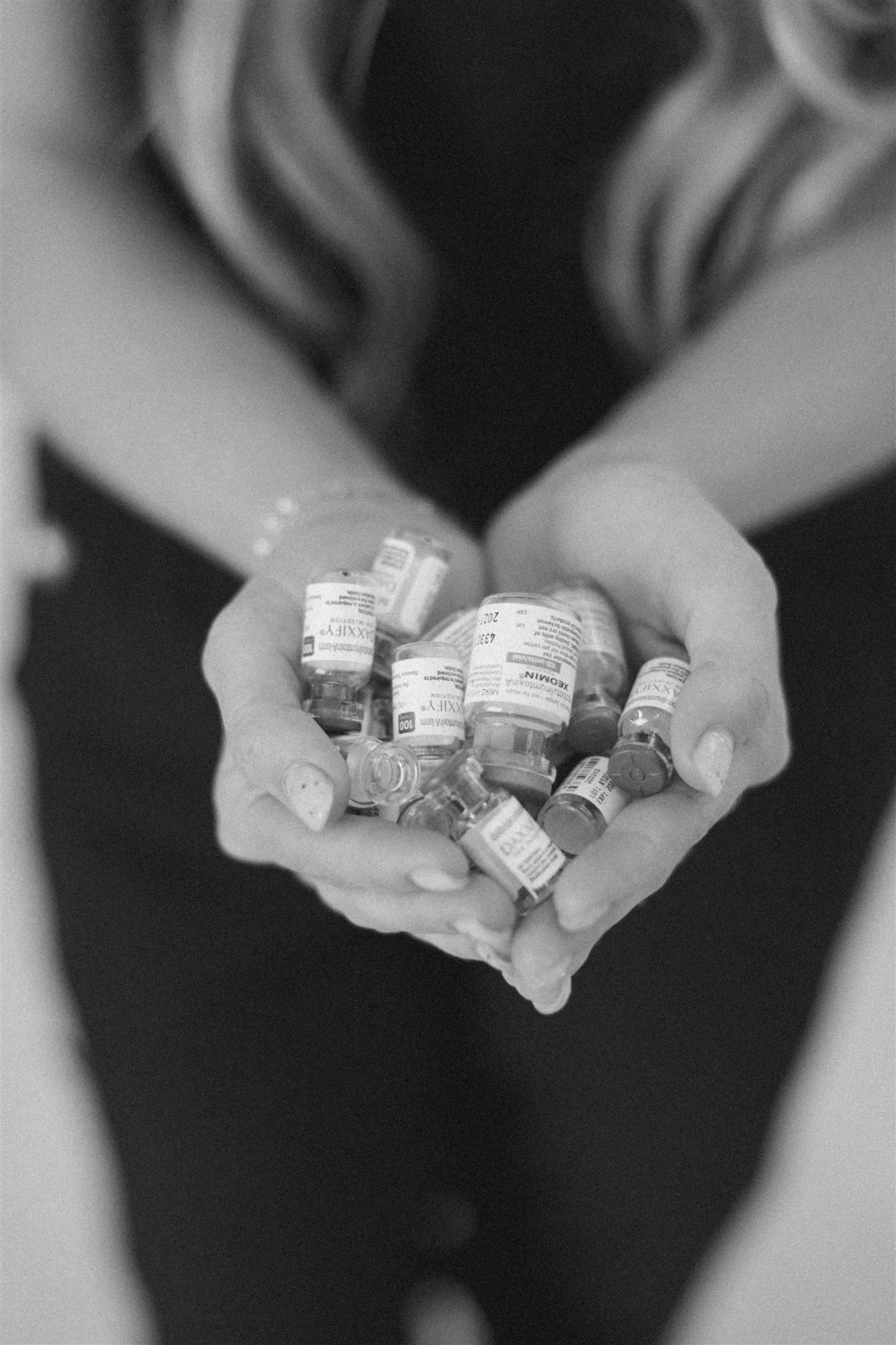Black and white image of hands holding small metallic cubes.
