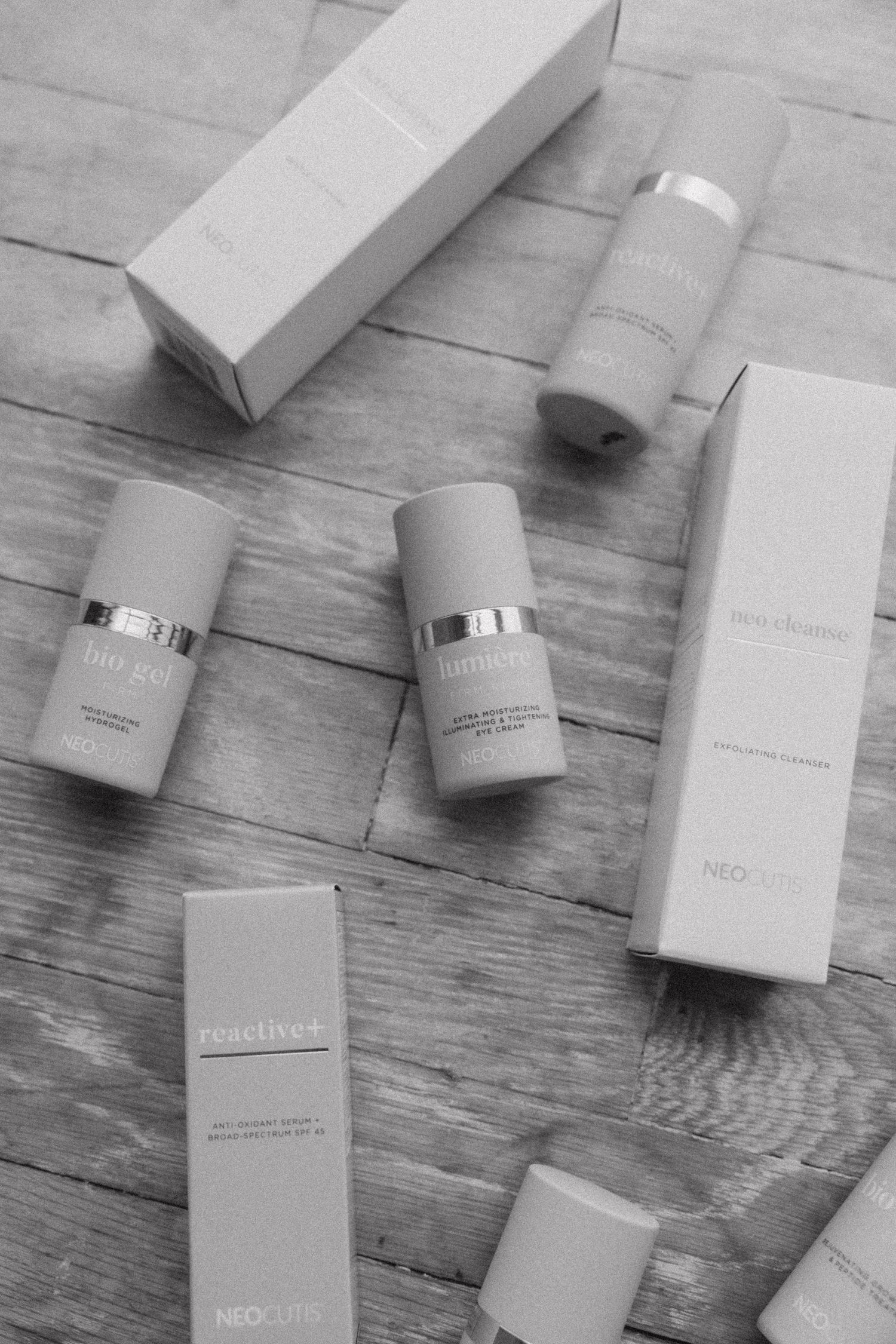 Collection of minimalist white skincare product bottles arranged on wooden surface.