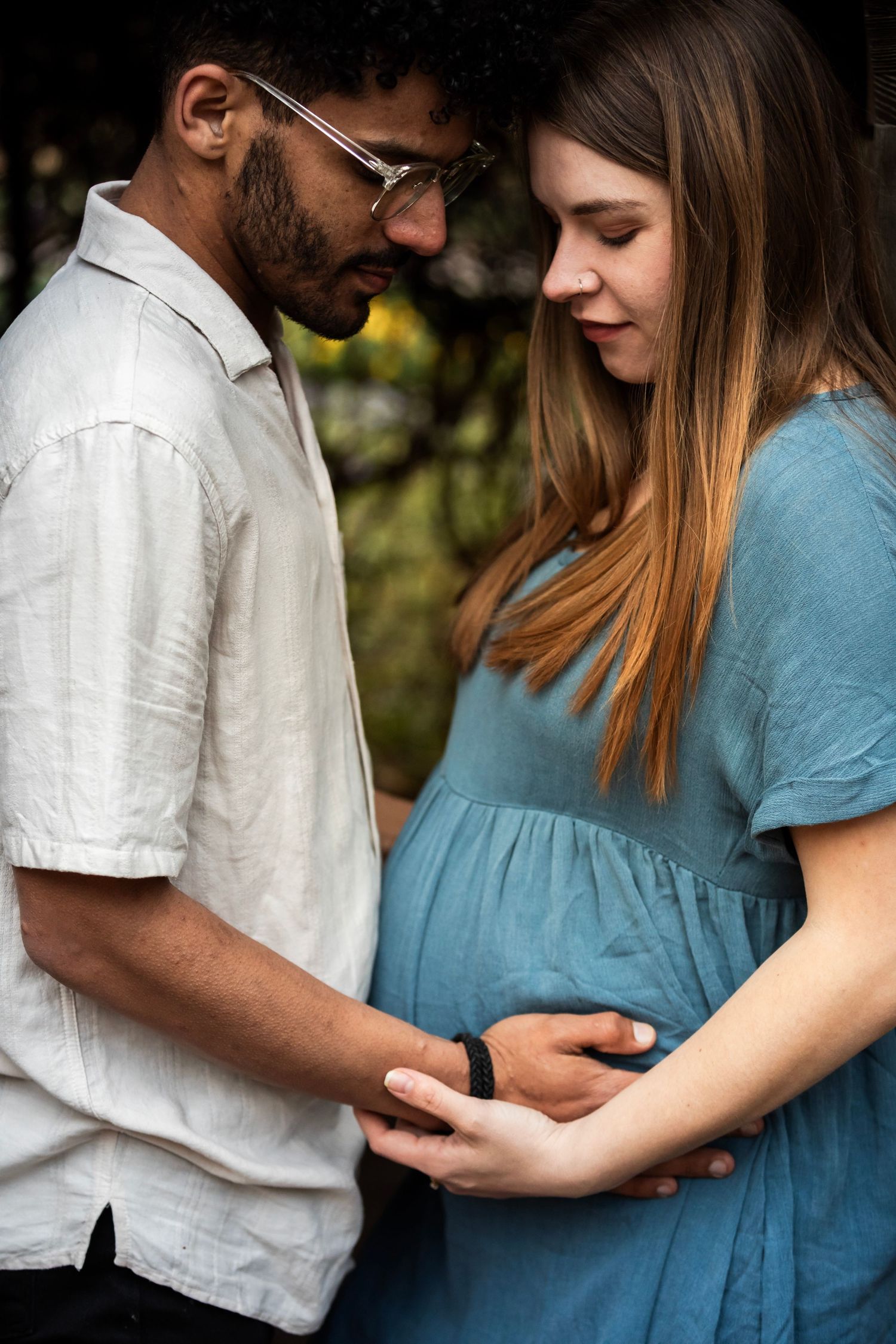 Expecting couple shares intimate moment while touching pregnant belly.