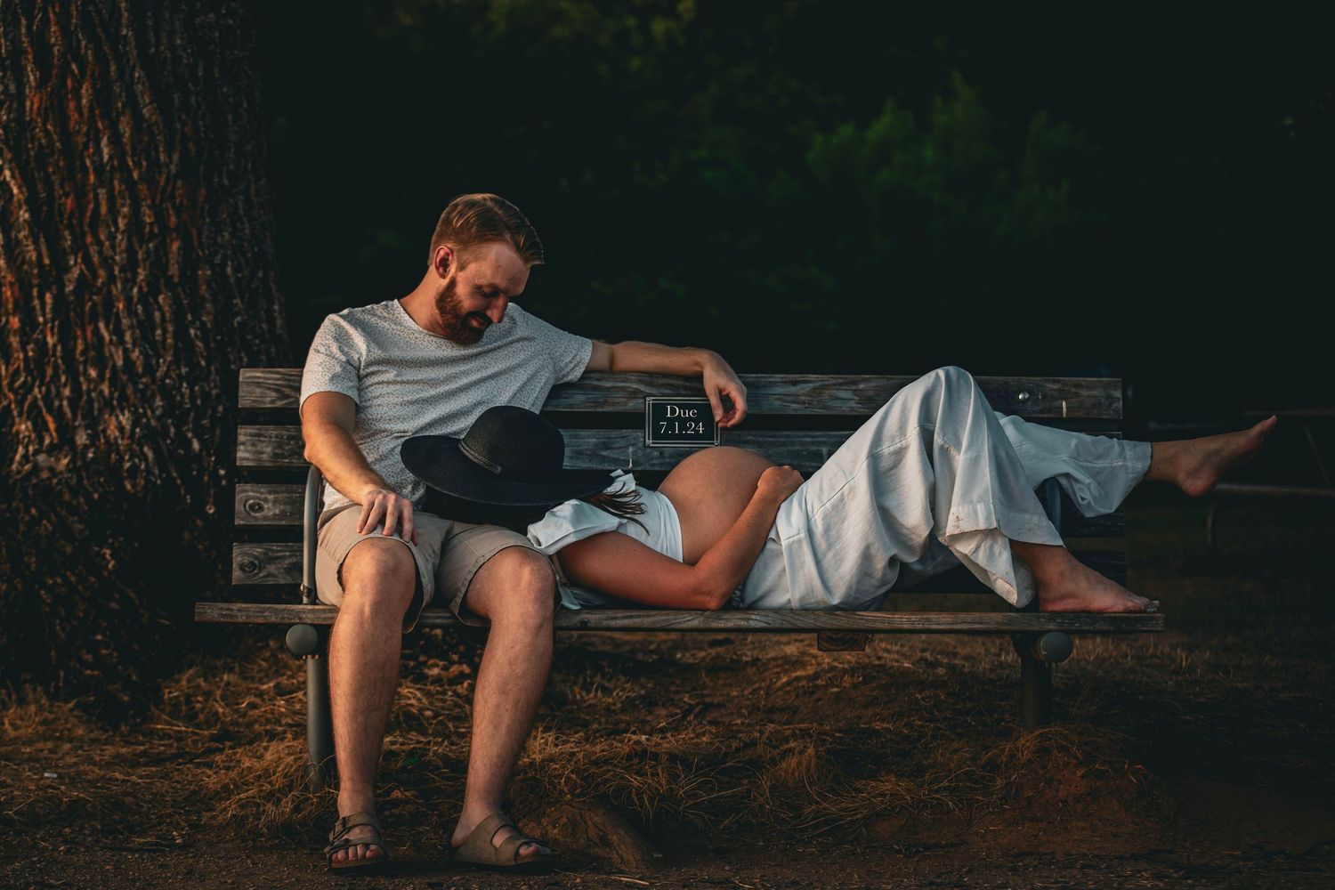 Two people relaxing on wooden bench in forest during sunset.