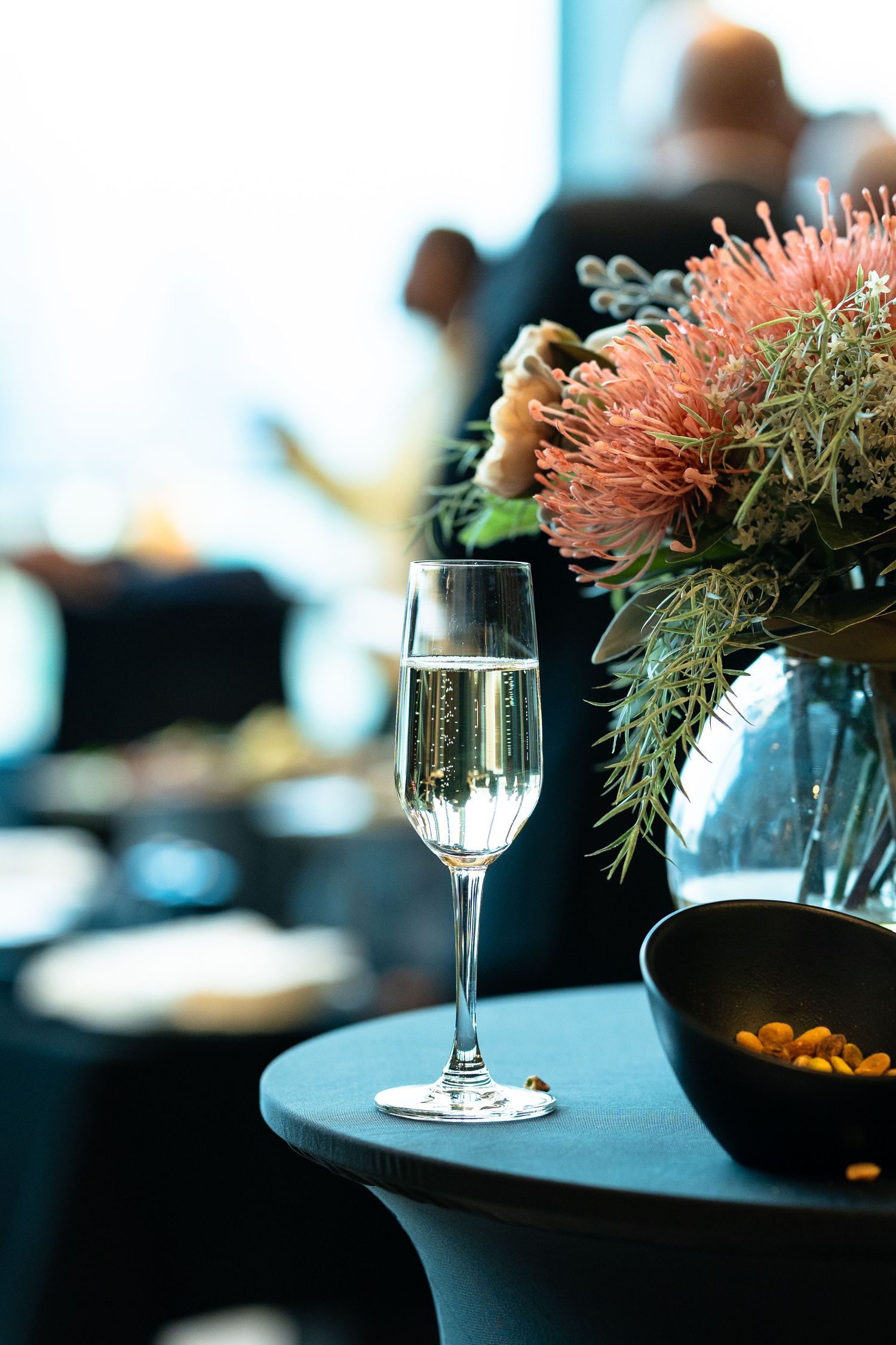 A champagne glass next to a vase with flowers