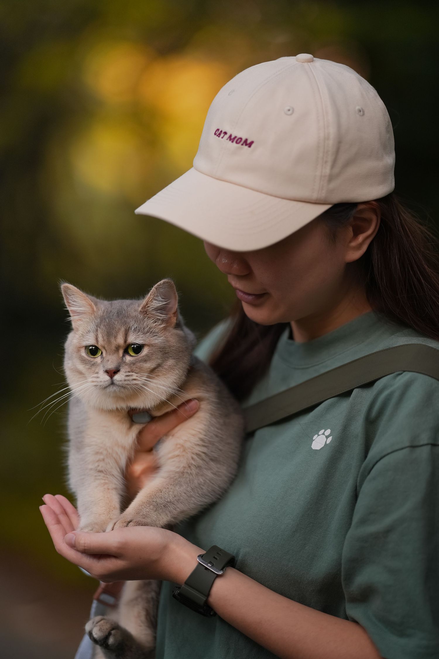 Grey cat being held outdoors shows various expressions of annoyance while being photographed.