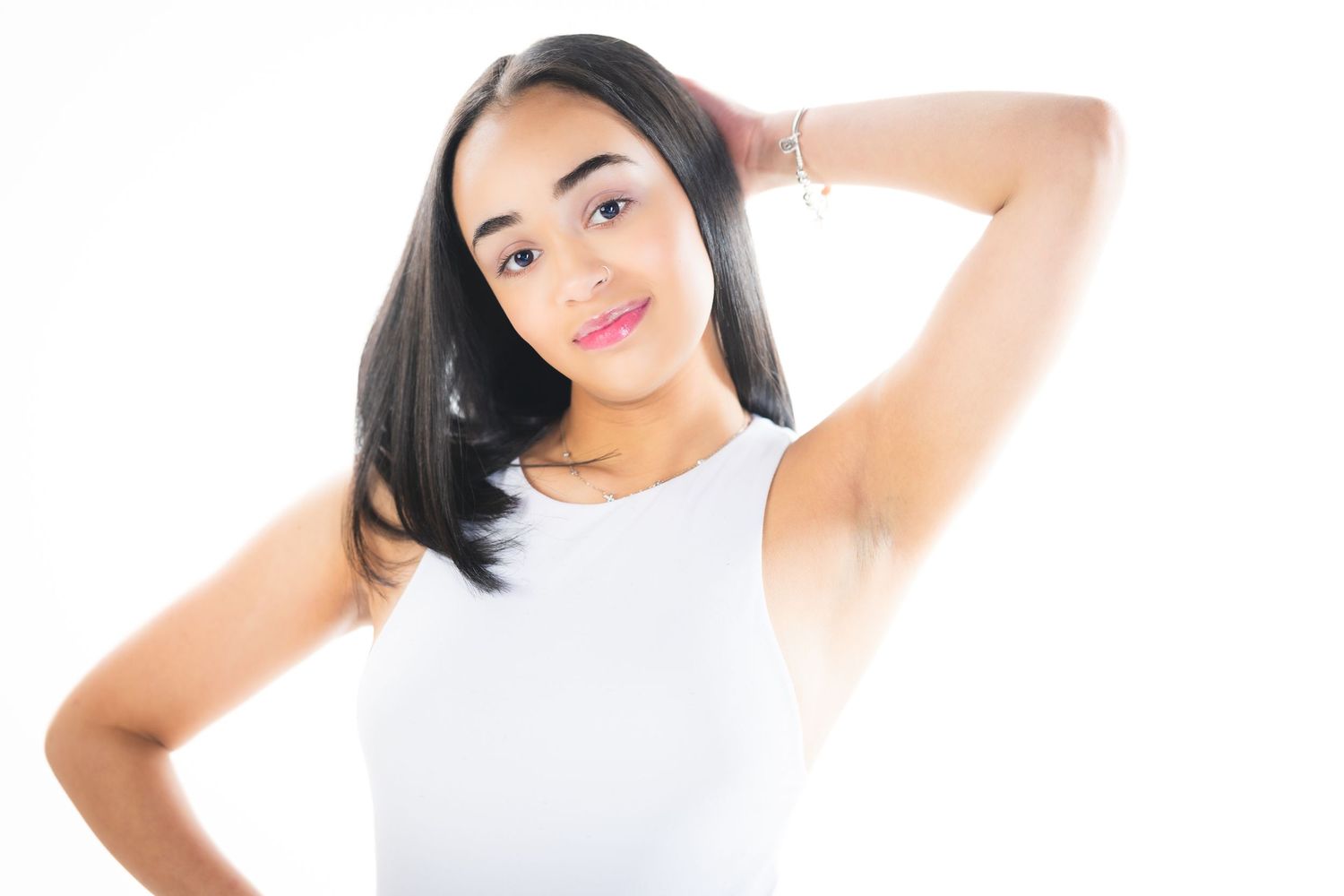 Portrait in white tank top against white background showing natural smile.