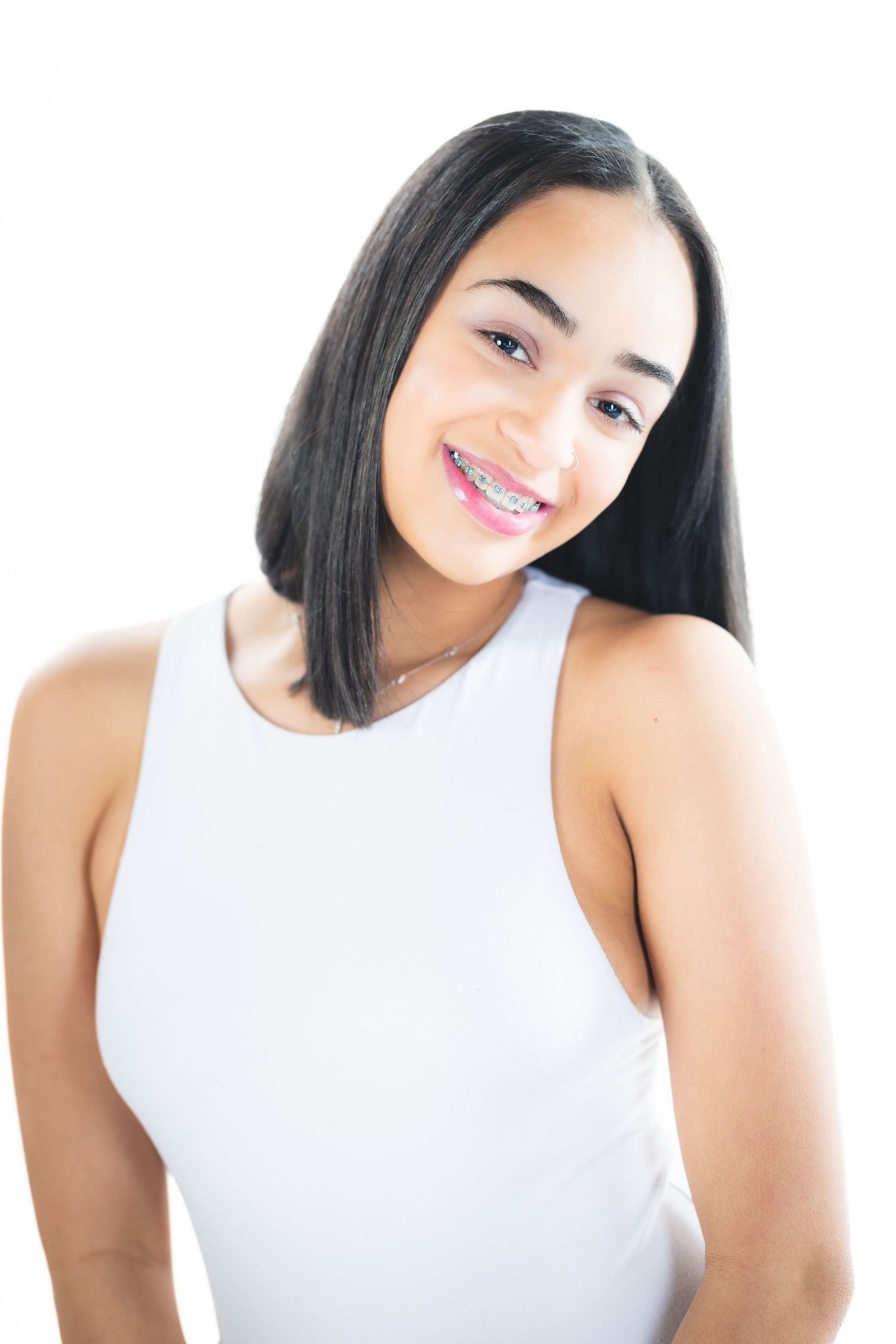 Studio beauty shot with straight dark hair and white sleeveless top.