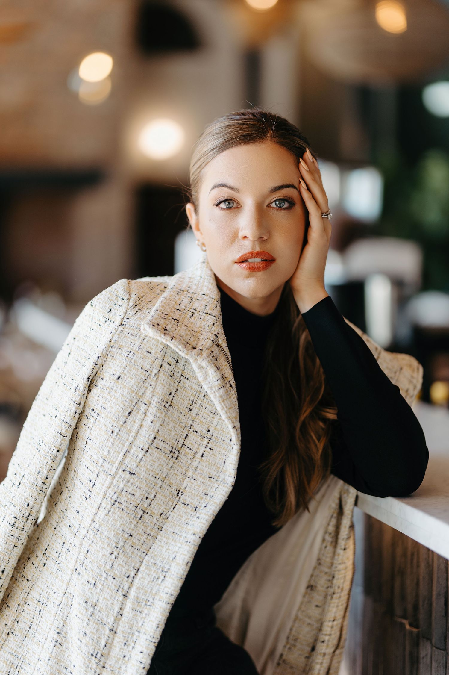 Fashion portrait with white textured blazer and black turtleneck sweater in warm indoor lighting.