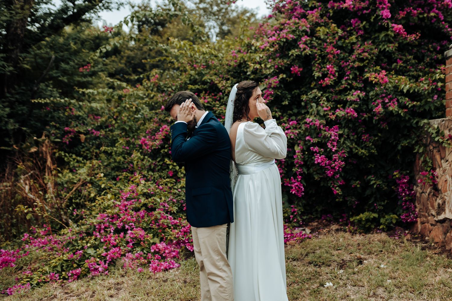 Playful wedding photo with couple pretending to drink while standing back to back.