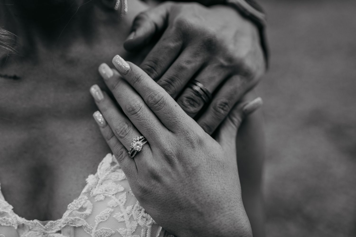 Black and white close-up of wedding rings and lace details.