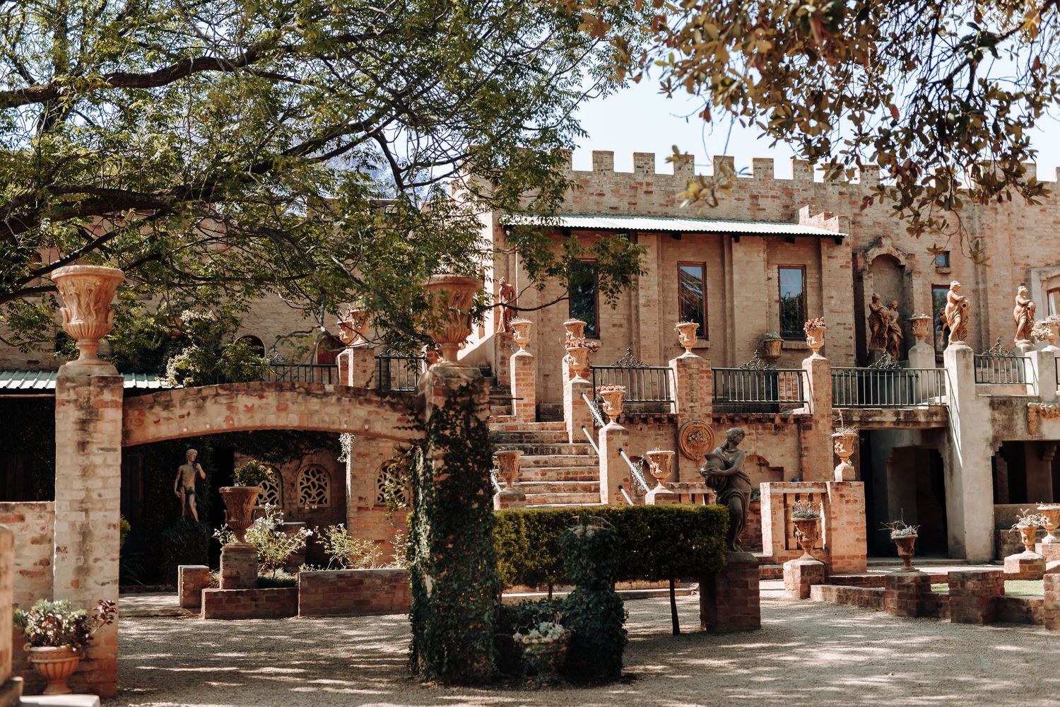 Historic brick building with colonial architecture and ornate balcony in courtyard setting.